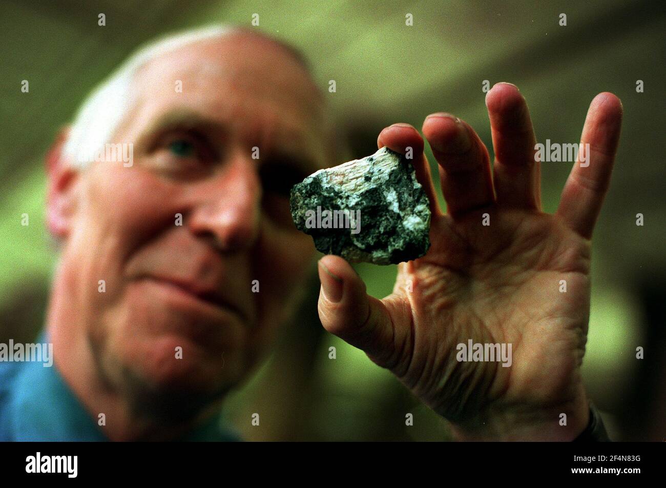 Dr Bob Symes December 1999at the national history museum holding a crystal of Symesute within a piece of mendipite in the mineral gallery Stock Photo