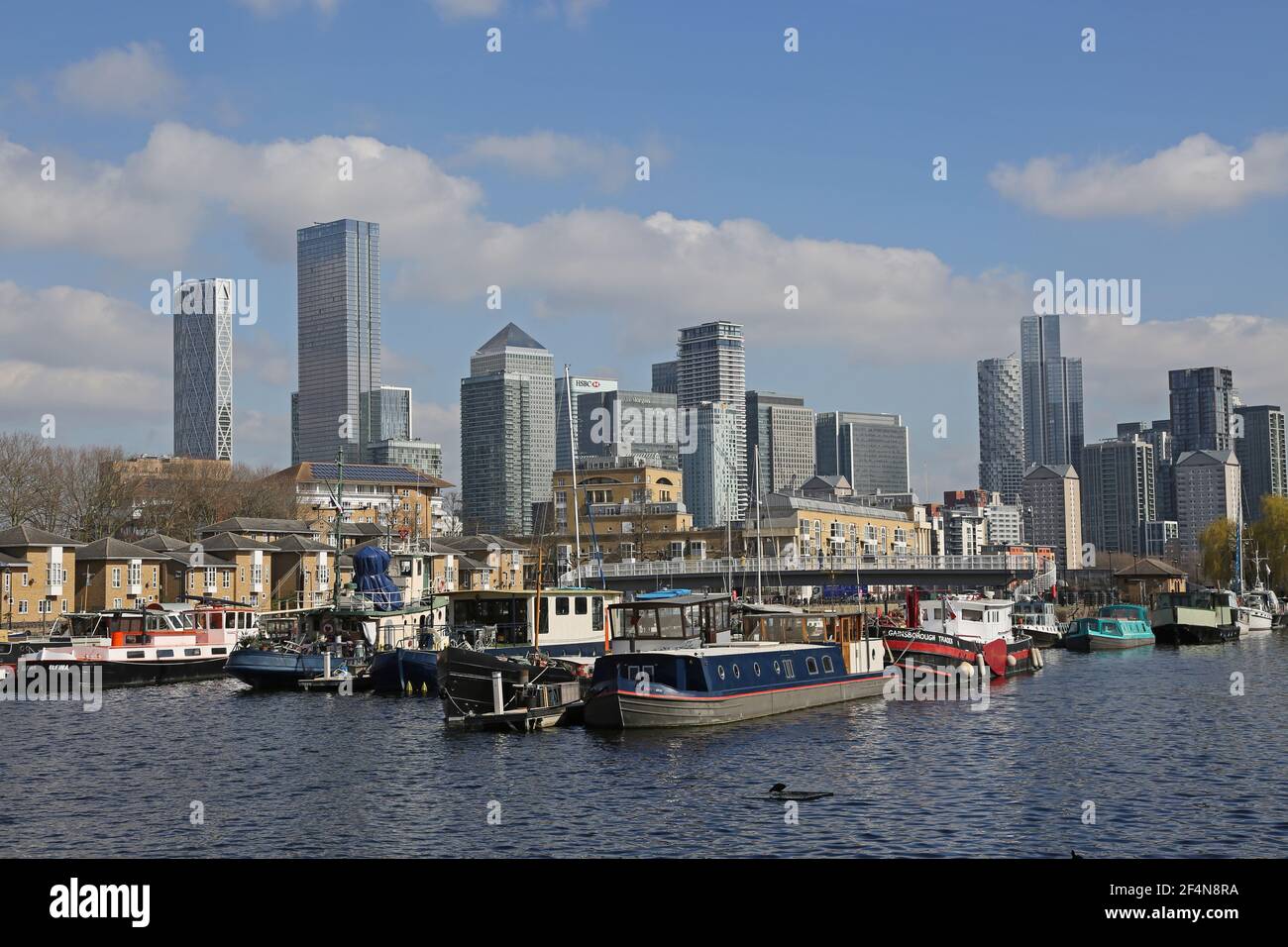 Houseboats in Greenland Dock, Rotherhithe, London, UK. Part of the  old Surrey Docks redeveloped in the 1980s. Canary Wharf towers in the background. Stock Photo
