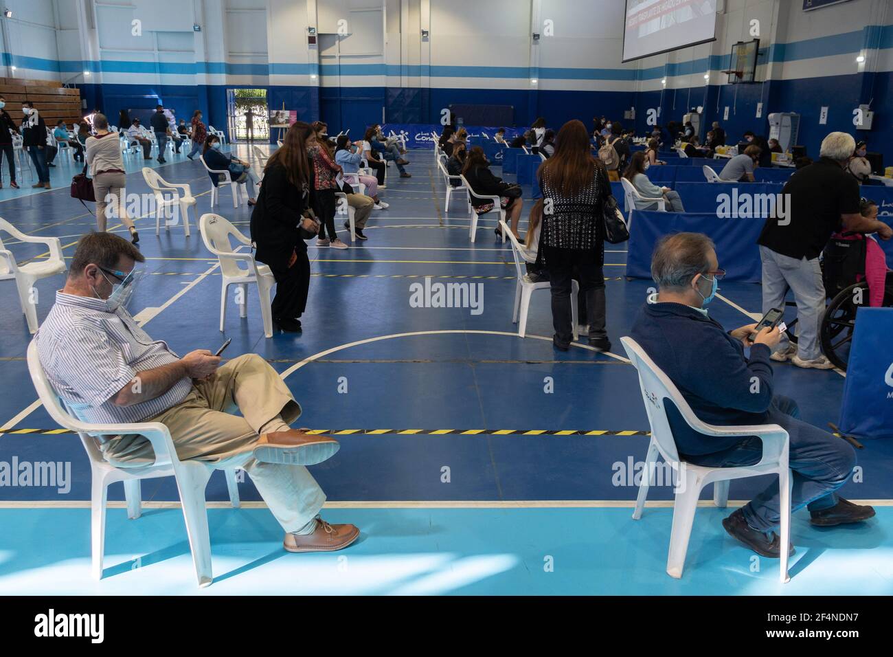 Santiago, Metropolitana, Chile. 22nd Mar, 2021. Two men wait in line to receive the dose of the Sinovac or Pfizer vaccine, in a municipal stadium transformed into a vaccination center against covid in Santiago de Chile. Credit: Matias Basualdo/ZUMA Wire/Alamy Live News Stock Photo