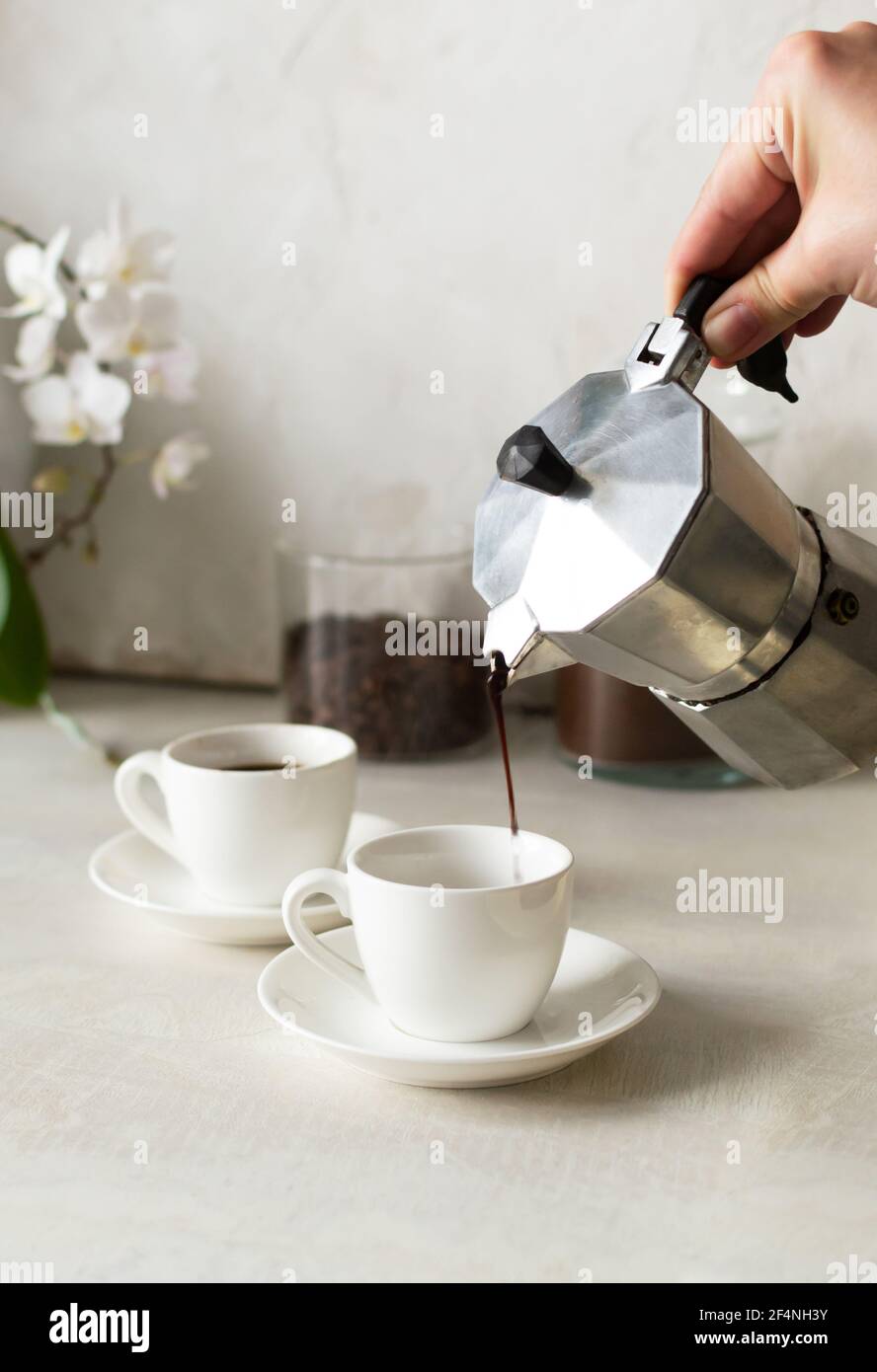 Coffee is poured from the geyser coffee maker into the espresso cup. Freshly brewed morning coffee concept. Vertical orientation. Stock Photo