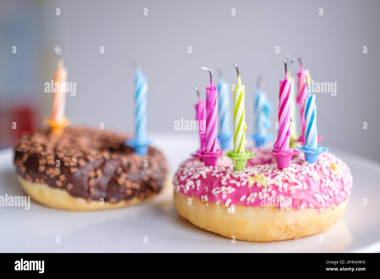 Colorful donuts with pink and chocolate icing with candles for birthday ...