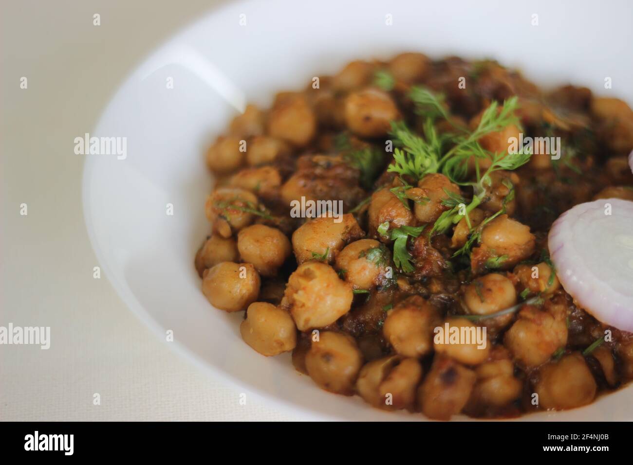 Spicy white chickpea gravy made by soaking chickpea overnight and cooked in a gravy of onions, tomatoes, ginger, garlic and spices. Shot on white back Stock Photo