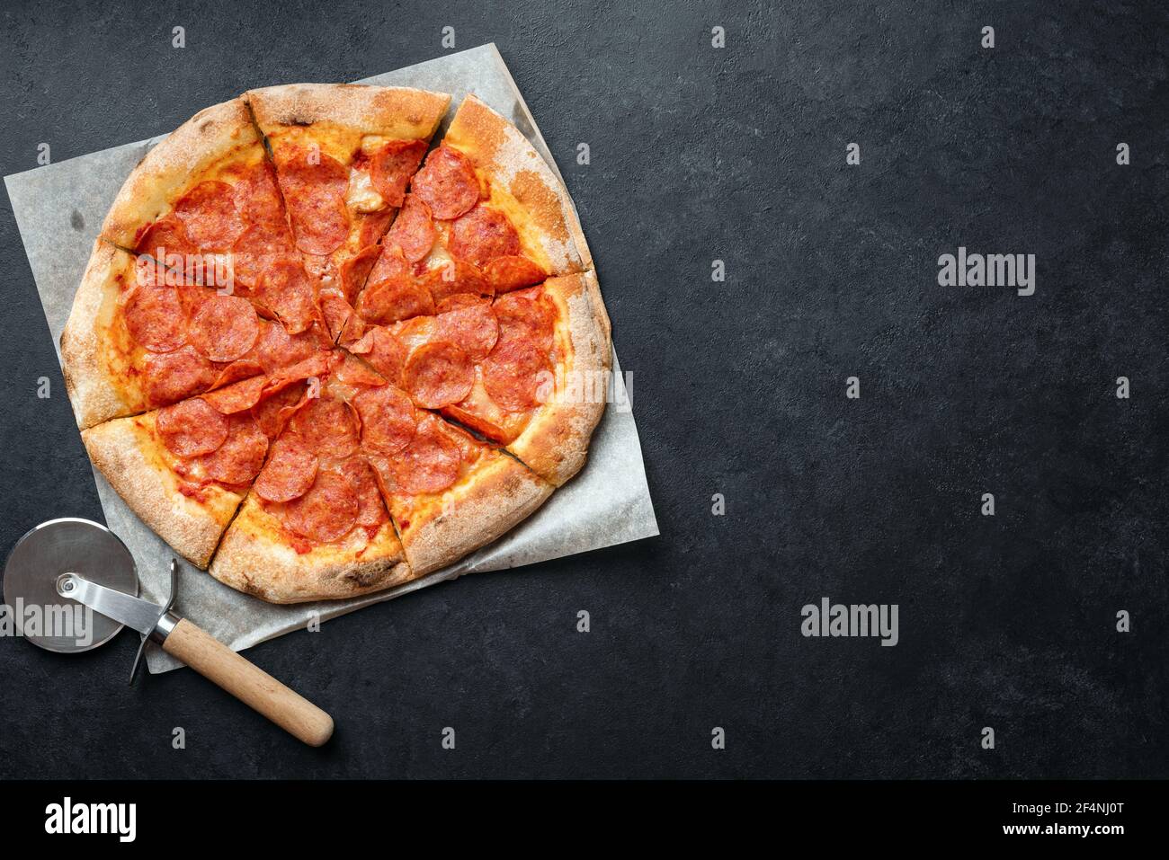 Tasty pepperoni pizza on black stone background. Pizza pepperoni cut into slices. Top view copy space for ad text or design Stock Photo