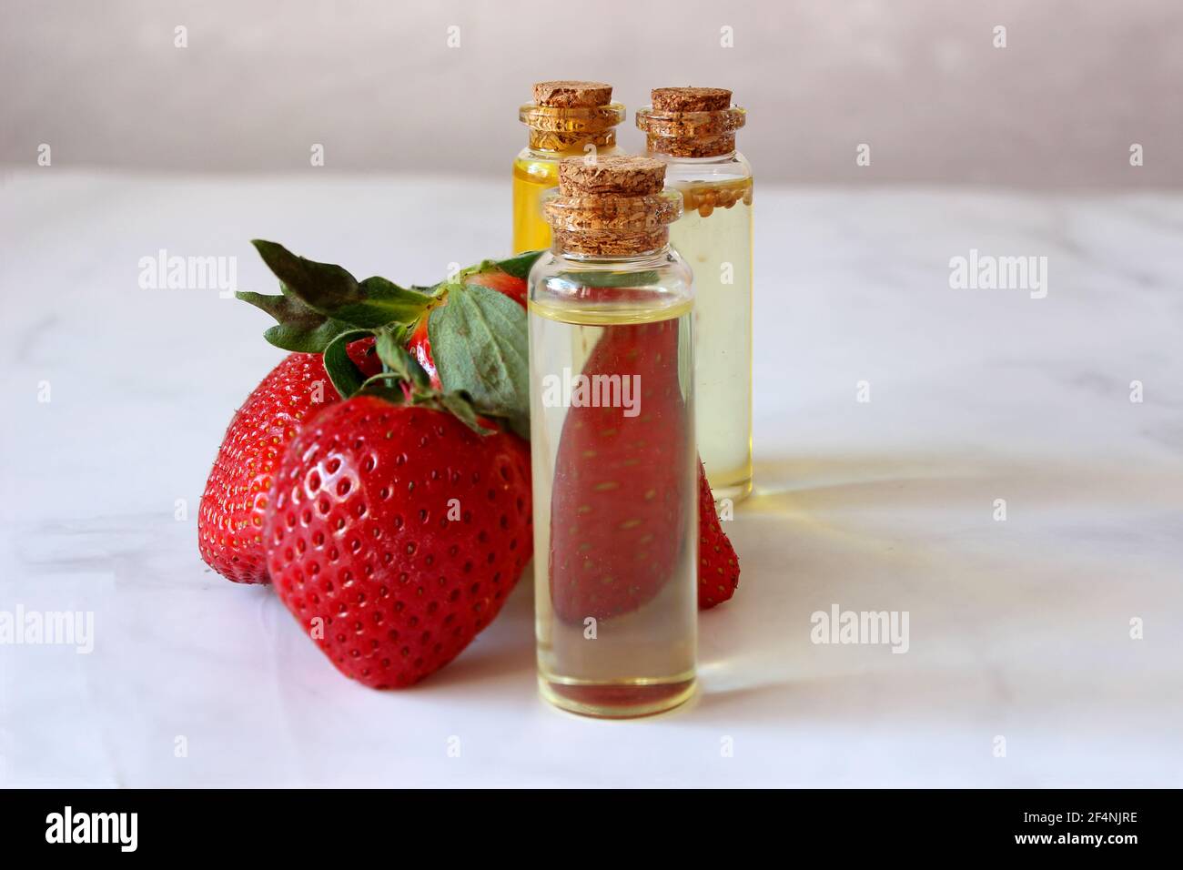 aroma and flavor enhancer next to ripe strawberries, on light background. Stock Photo