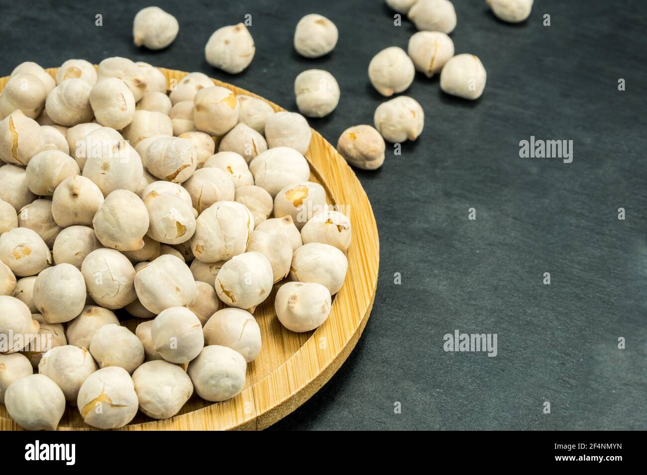 White chickpeas scattered on a black stone background. Stock Photo