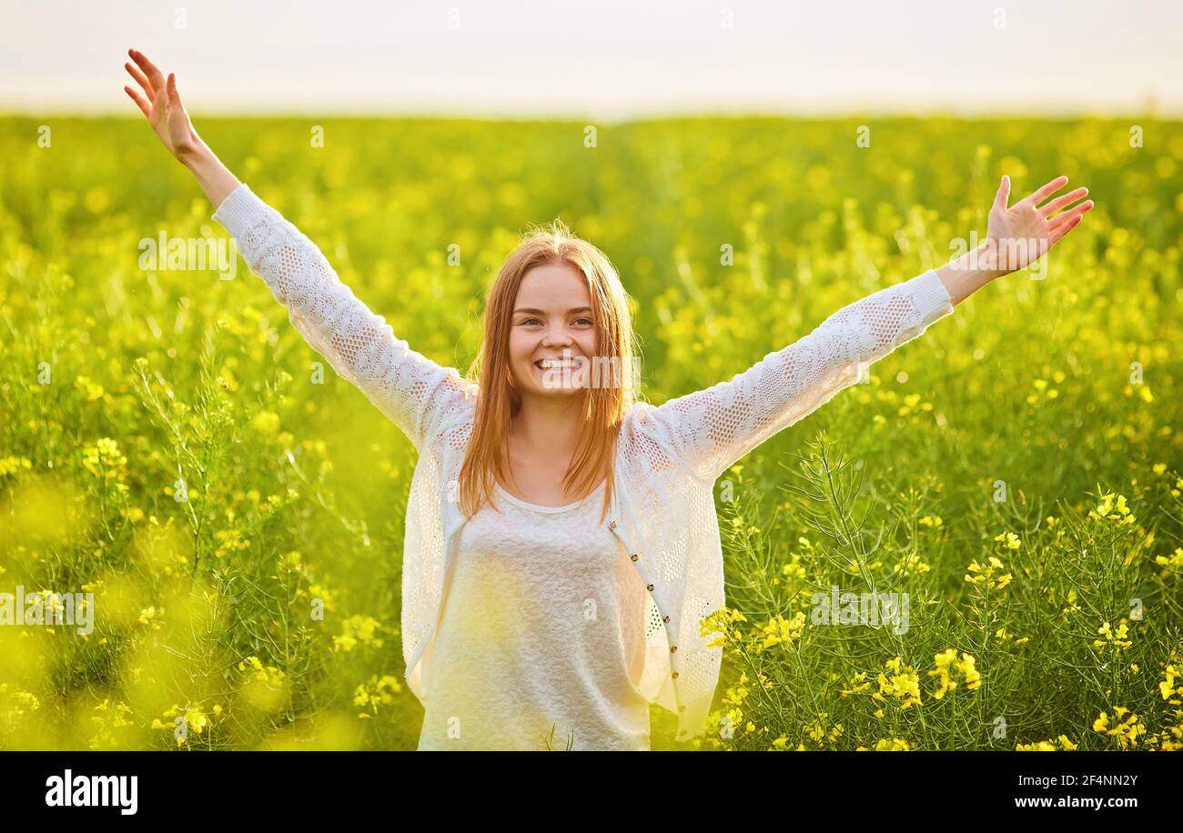 Redhead girl in a rapeseed field, on a sunny day Stock Photo - Alamy