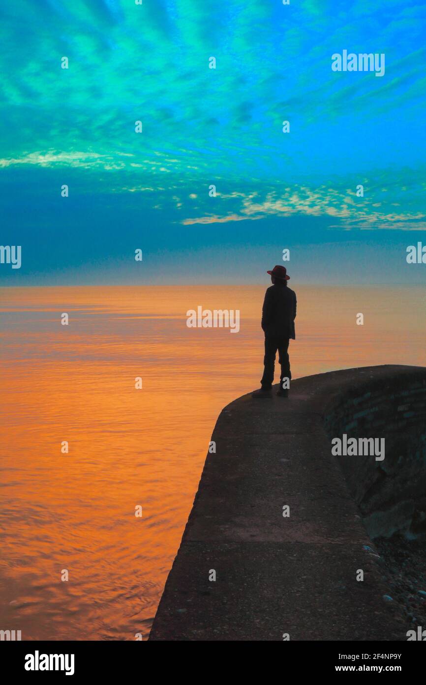 Silhouette of a man standing on jetty at sunrise. Book cover concept. Stock Photo