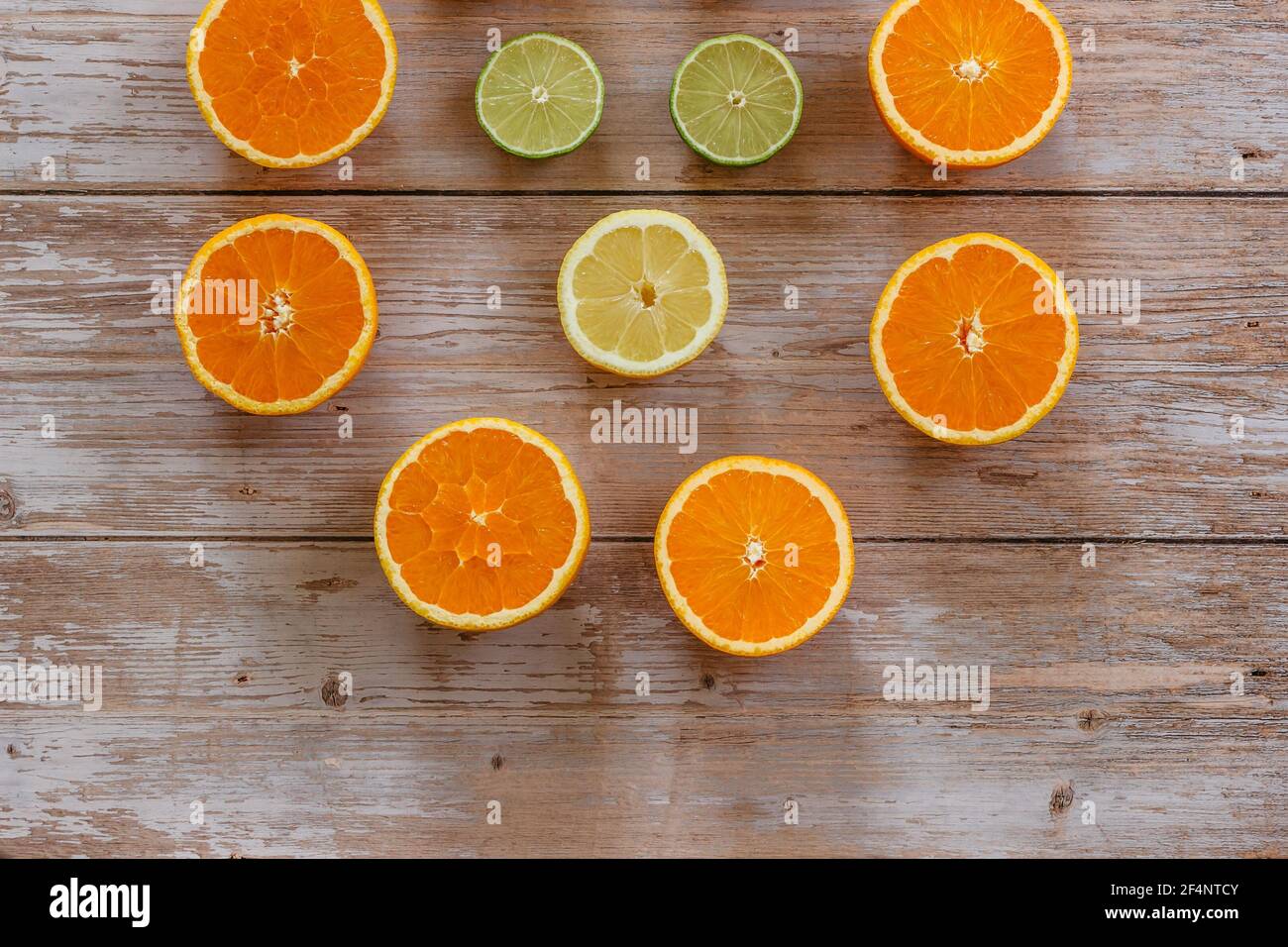 Oranges,limes and lemons slides on wooden table view from above.Beautiful background with fresh fruit half cut.Healthy eating vitamin C.Summer tropic Stock Photo