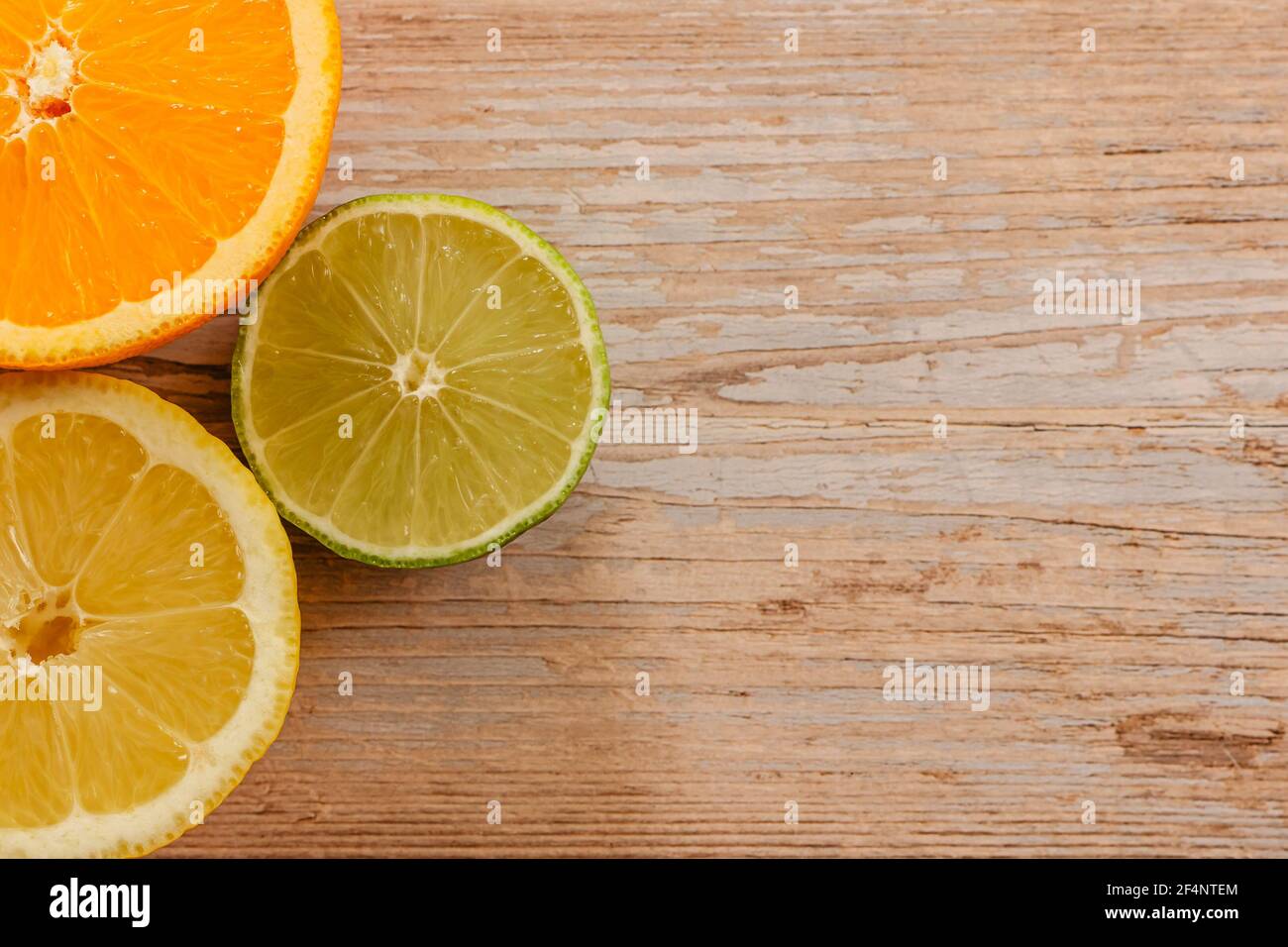 Oranges,limes and lemons slides on wooden table view from above.Beautiful background with fresh fruit half cut.Healthy eating vitamin C.Summer tropic Stock Photo