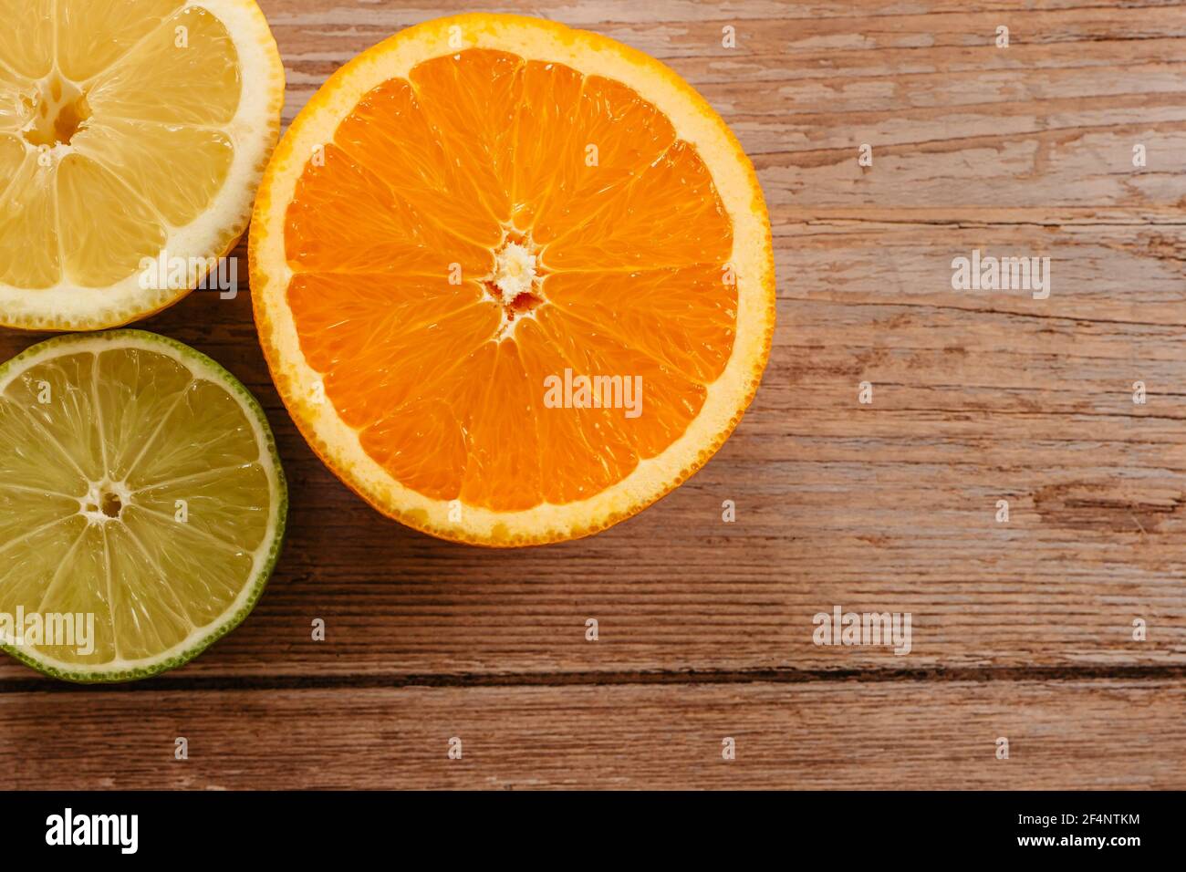 Oranges,limes and lemons slides on wooden table view from above.Beautiful background with fresh fruit half cut.Healthy eating vitamin C.Summer tropic Stock Photo