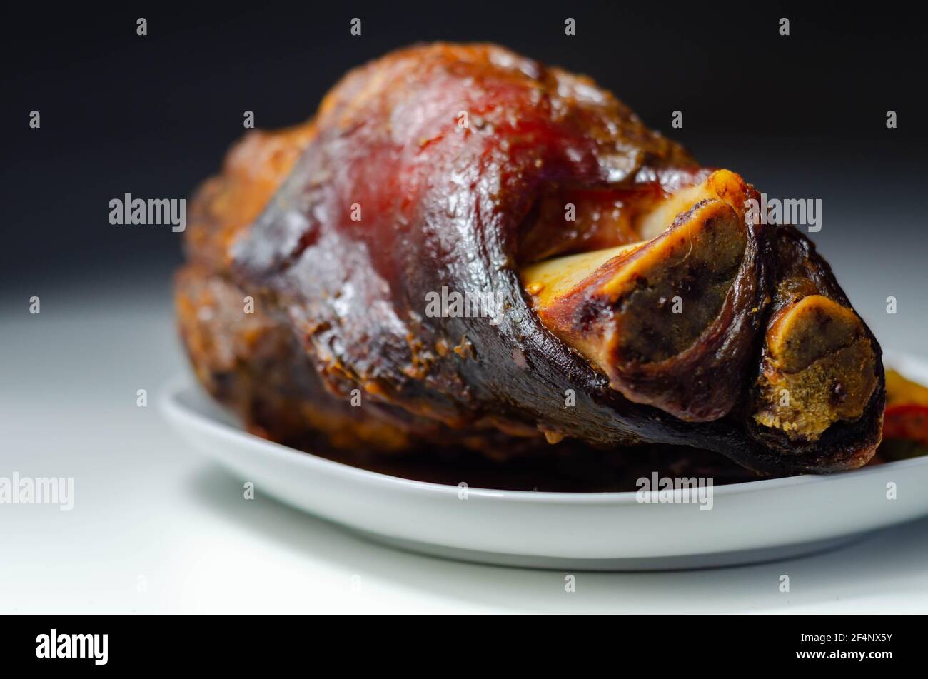 Bacon joint with bone served with grilled vegetables, red and yellow
