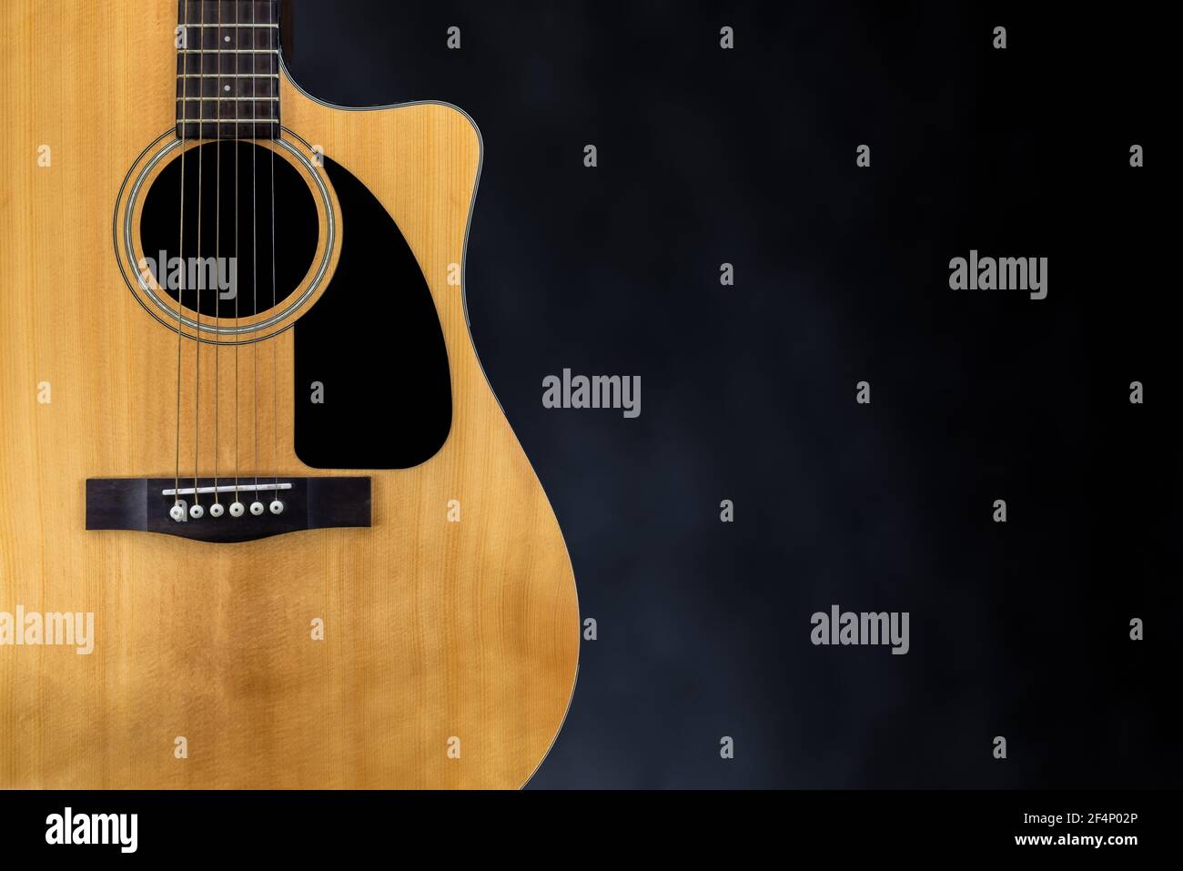 sound board of classic yellow acoustic guitar with black pickguard and strings near isolated black background Stock Photo