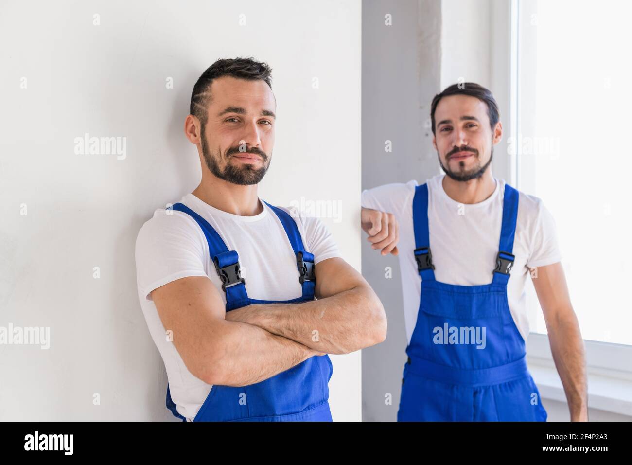 Two builders in blue work clothes smile a little Stock Photo