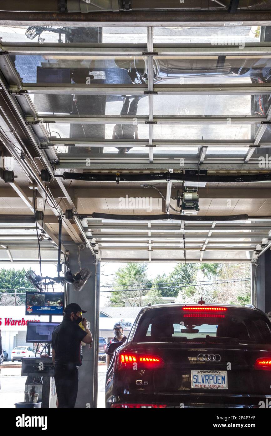 Two Valvoline employees at work help a customer in a car in Asheville