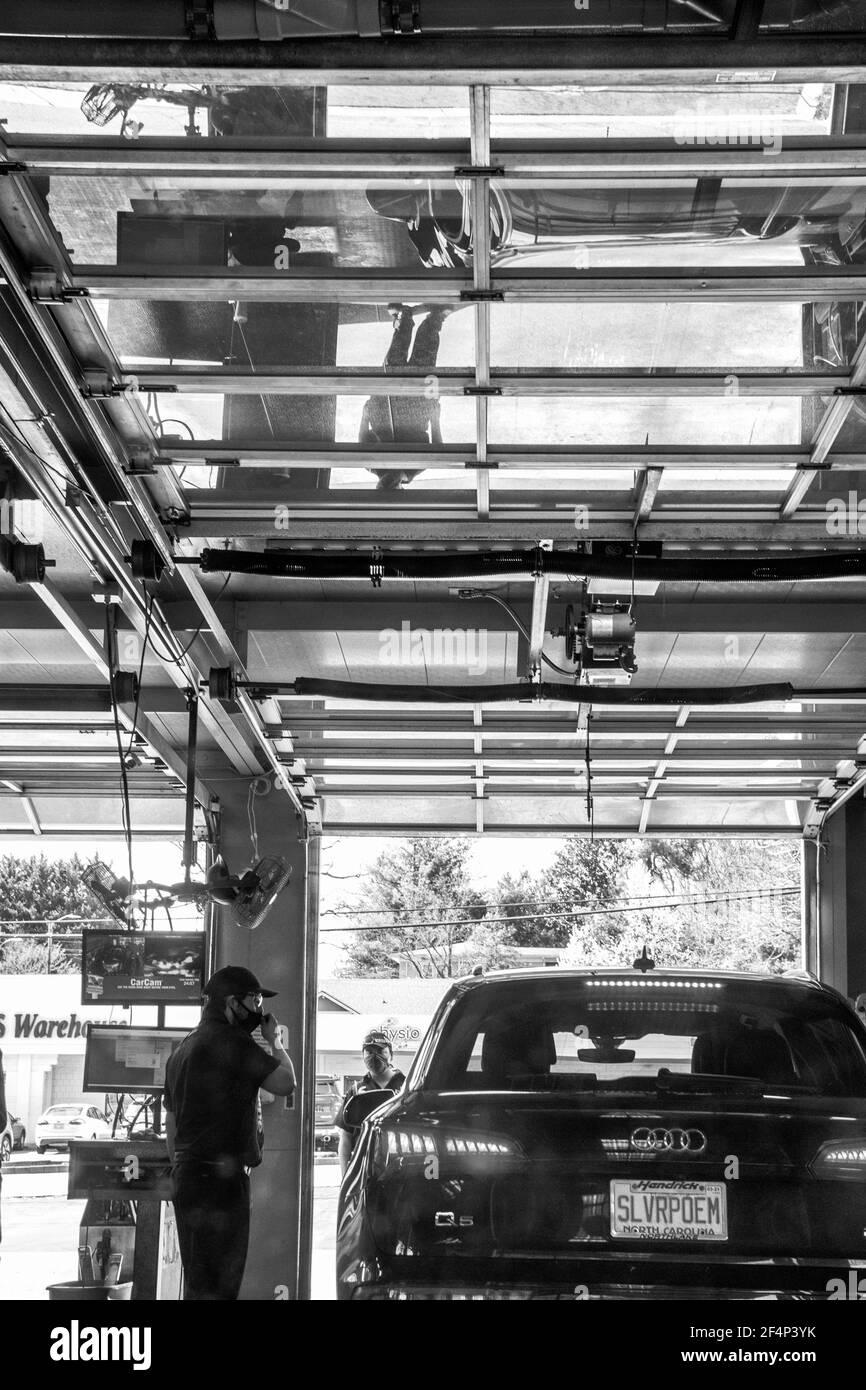 Two Valvoline employees at work help a customer in a car in Asheville, NC, USA Stock Photo