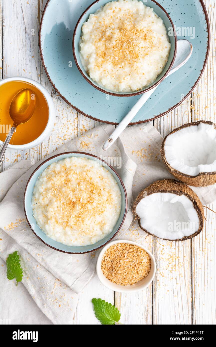 Sweet and creamy coconut rice pudding with honey, topped with grated and toasted coconut in a ceramic bowl Stock Photo