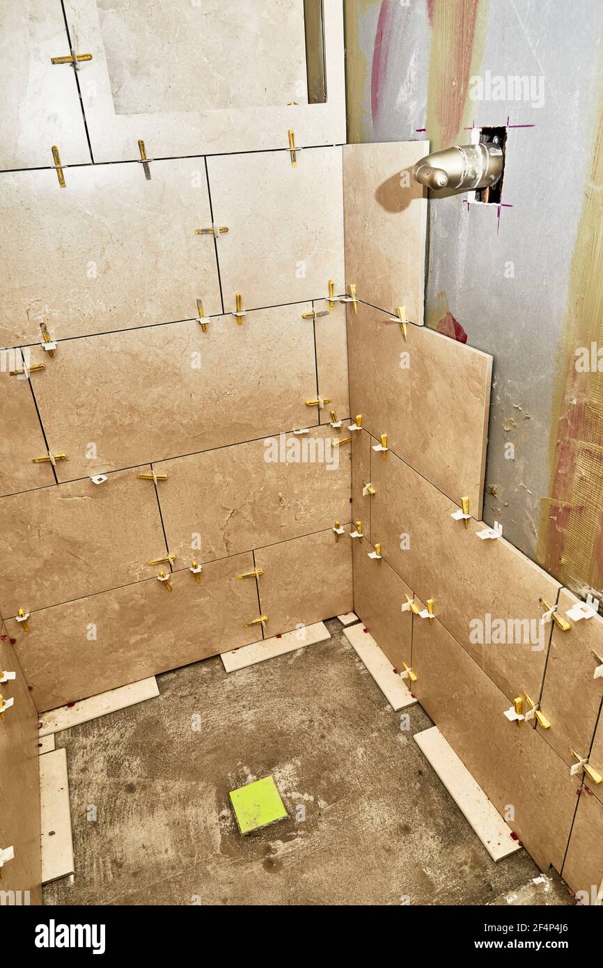 shower stall wall with grout spacers in preparation for new porcelain tile installation Stock Photo