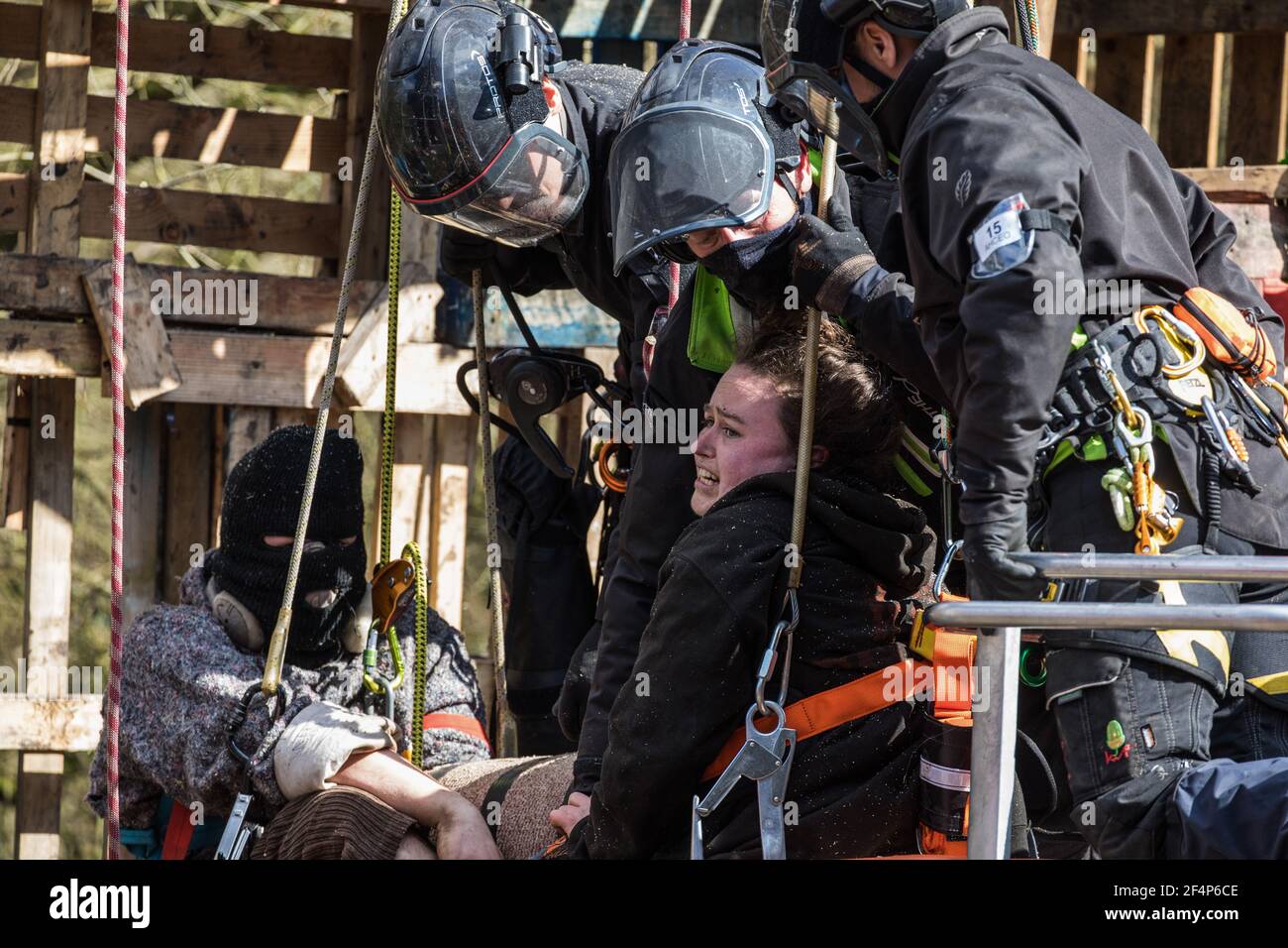 Denham, UK. 22nd March, 2021. Bailiffs from the National Eviction Team (NET) work to remove two anti-HS2 activists who are locked together from a makeshift tower in Denham Country Park where they had been seeking to delay electricity pylon relocation works by Babcock in connection with the high-speed rail project. The activist on the right is calling out to complain about the manner in which she is being touched by one of the male bailiffs. Credit: Mark Kerrison/Alamy Live News Stock Photo