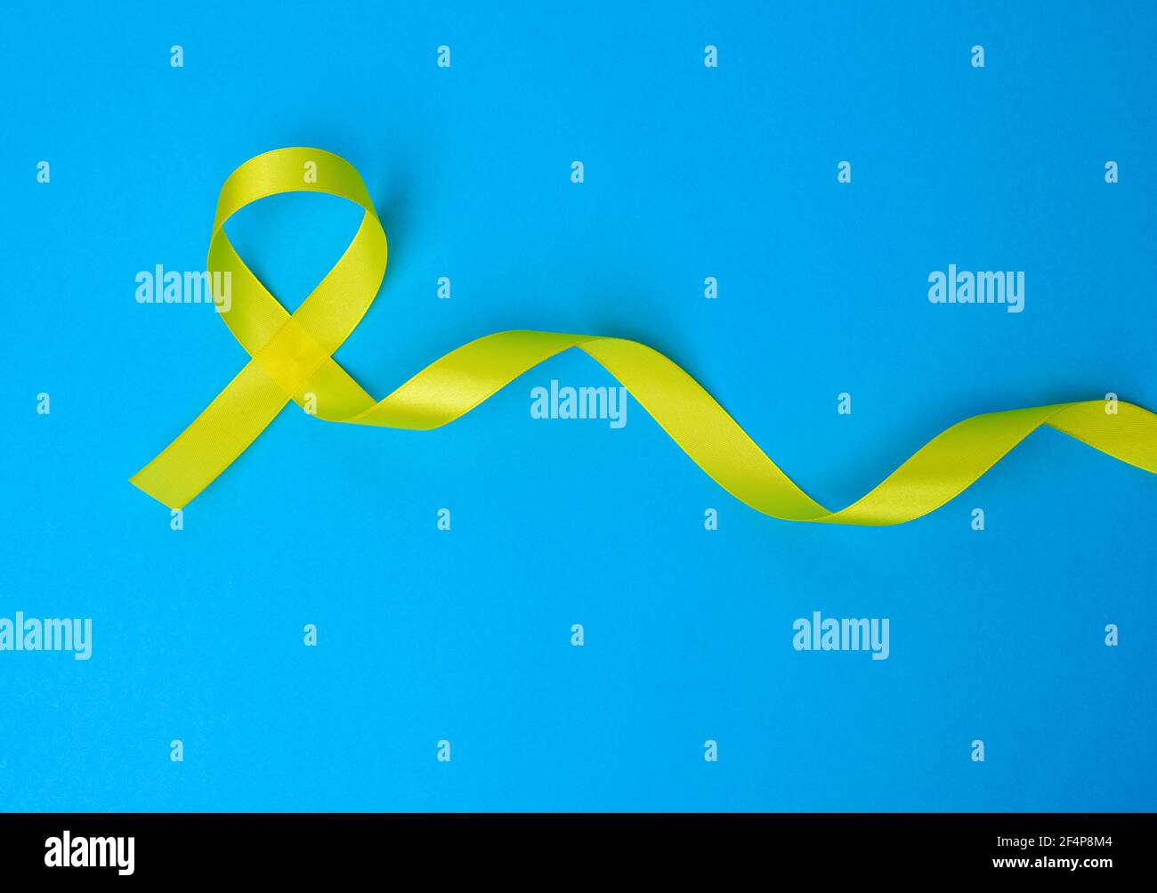 yellow silk ribbon loop on a blue background. Sarcoma bone cancer awareness, top view Stock Photo
