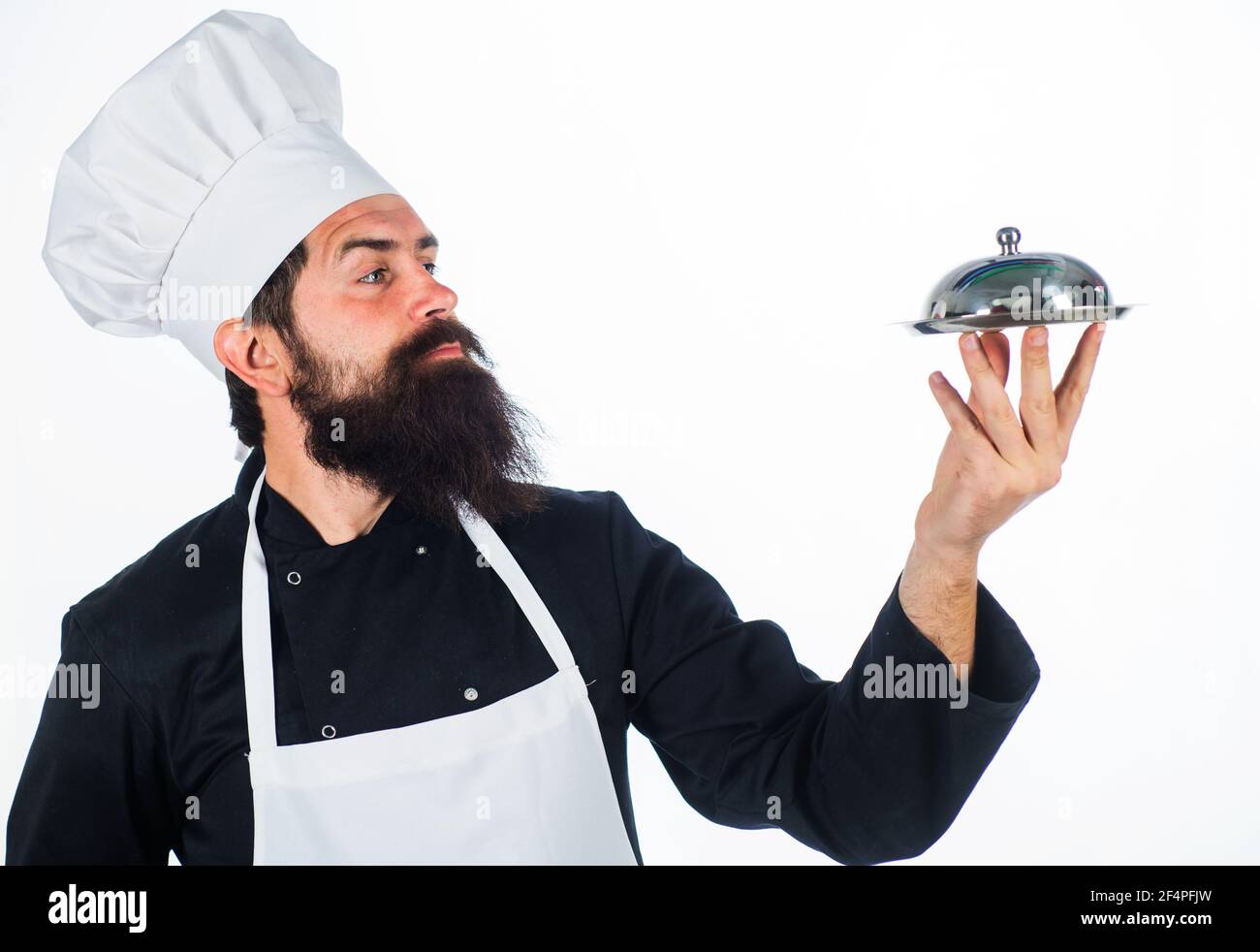 Restaurant Serving and presentation. Bearded chef with food tray. Cook holds metallic dish. Stock Photo