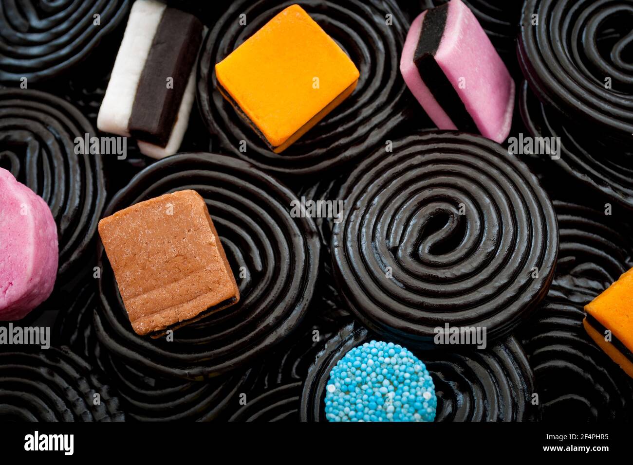 Black liquorice swirls, chewy candy and delicious dessert concept with macro close up on licorice wheels and other assorted licorice with a mix of col Stock Photo