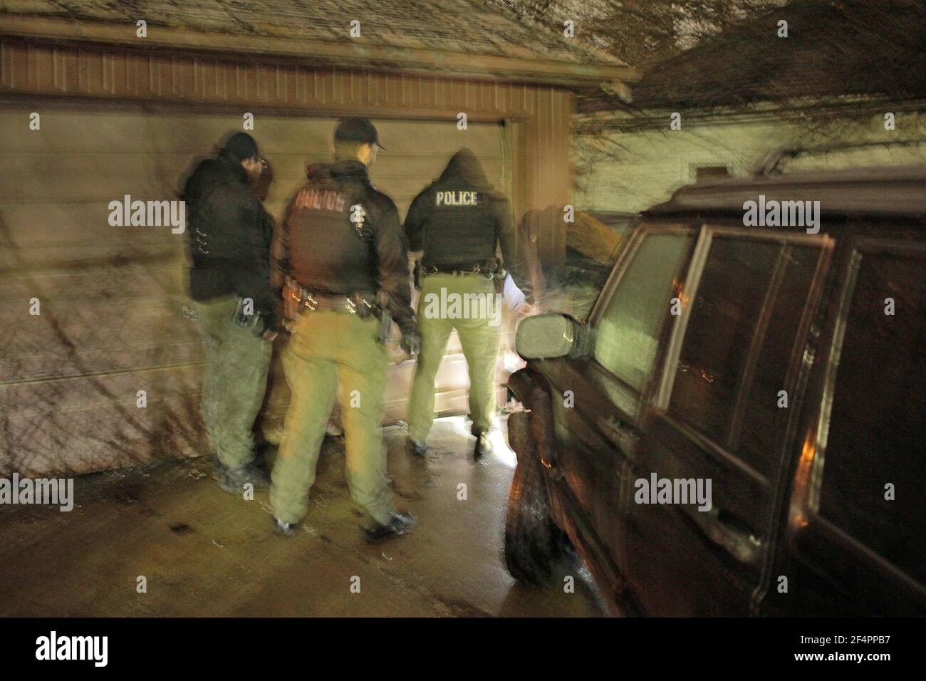 Police officers search the back yard of a building at night, Detroit, Michigan, USA Stock Photo