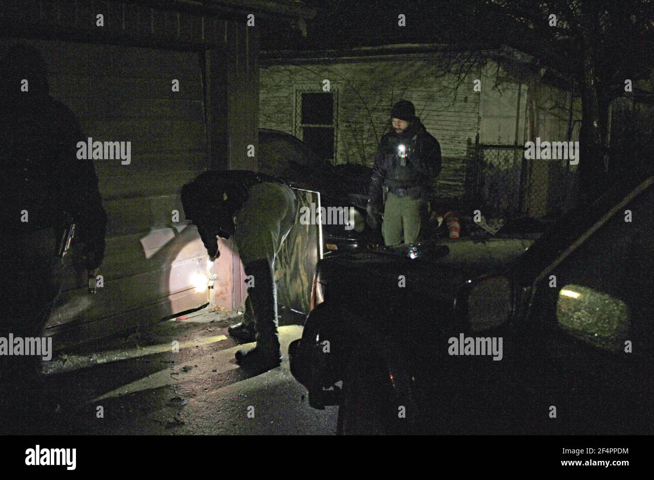 Police officers search the back yard of a building at night, Detroit, Michigan, USA Stock Photo