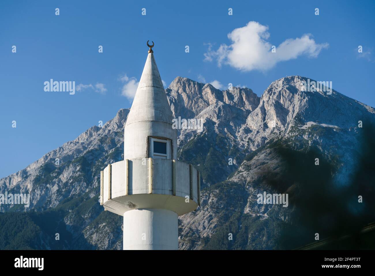 Minaret tower of a mosque in front of sunny rocky Austrian alps in Telfs, Tirol, Austria Stock Photo