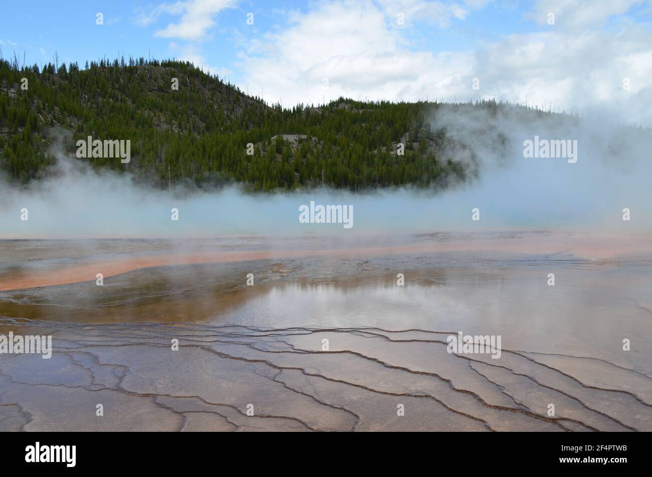 Late Spring in Yellowstone National Park: Grand Prismatic Spring with Surrounding Mat and Steam Hovering in the Excelsior Group of Midway Geyser Basin Stock Photo