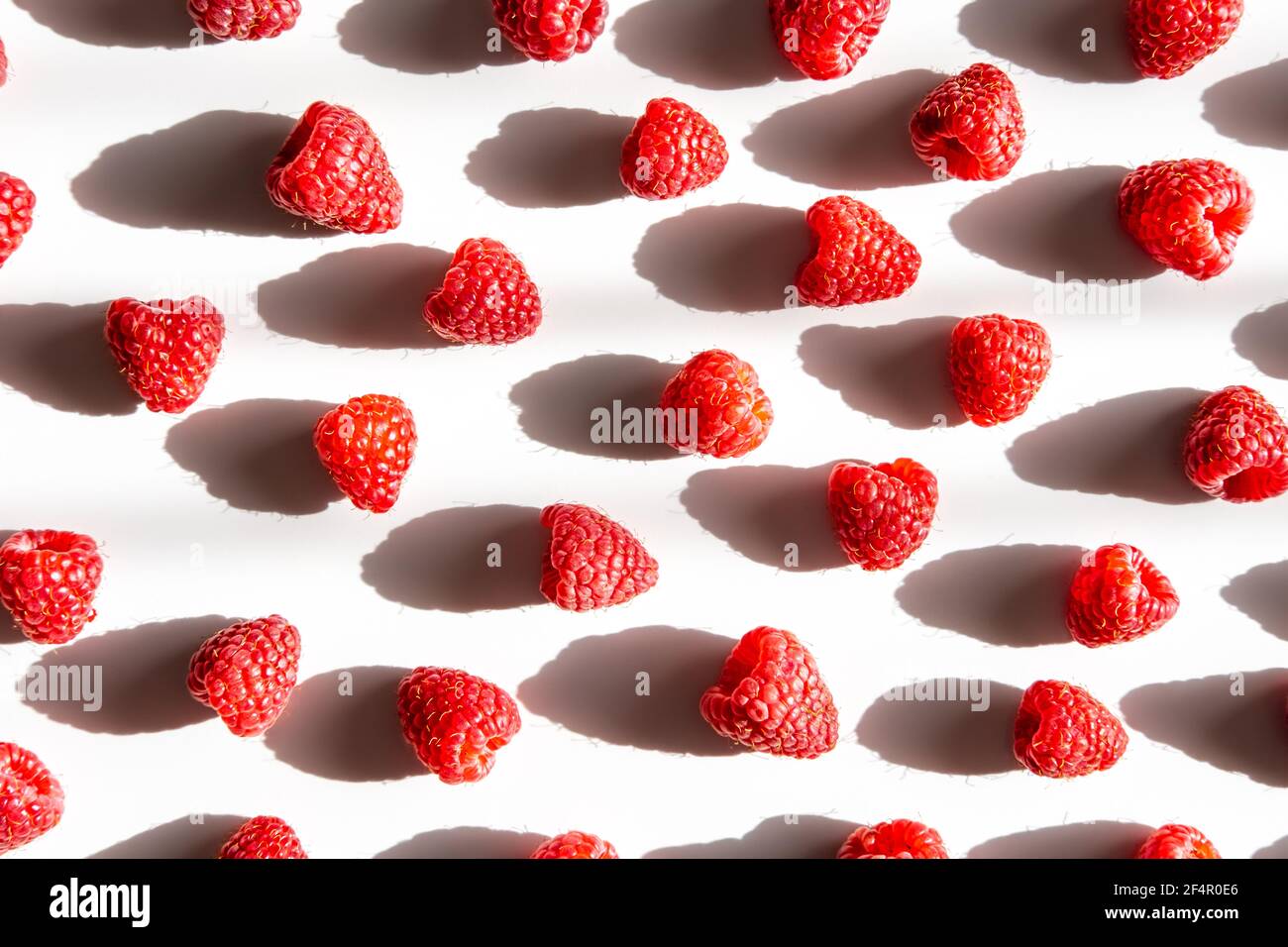 Pattern of fresh raspberry with shadow on light background. Flat lay. Stock Photo
