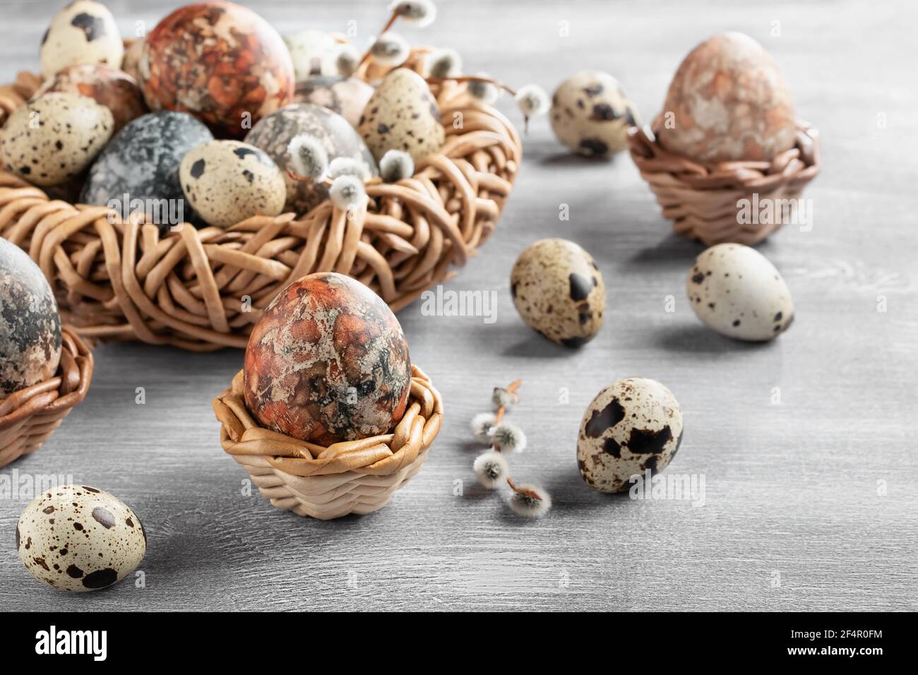 Easter composition - several marble eggs painted with natural dyes in a wicker nest and baskets. Stock Photo