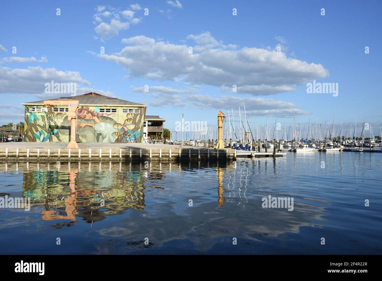 Water reflection of the sailboats and building with mural on the wall on a cloudy but sunny day near St. Pete pier. St. Petersburg, Florida, USA Stock Photo