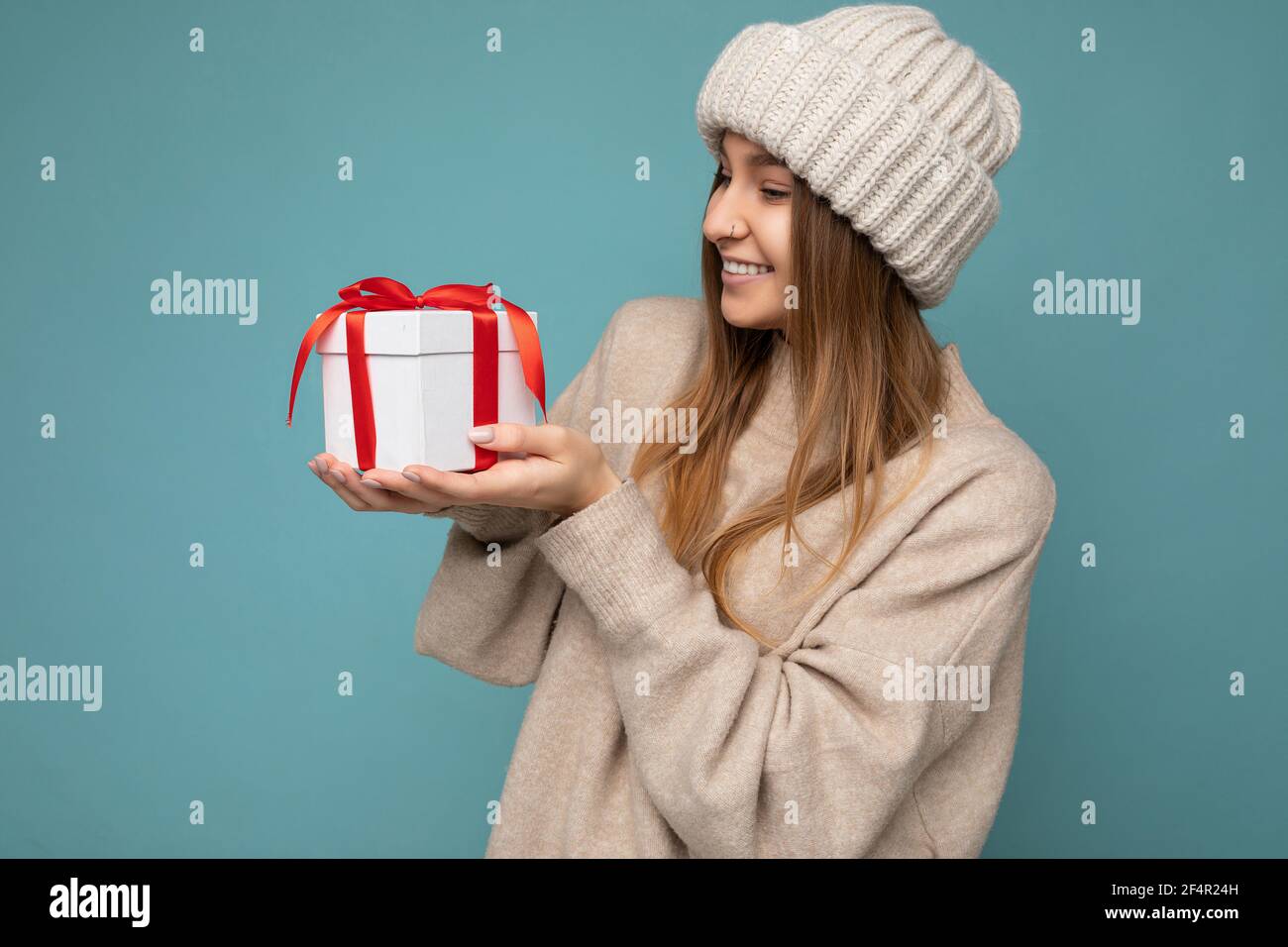 Shot of attractive positive smiling young dark blonde woman isolated over colourful background wall wearing everyday trendy outfit holding gift box Stock Photo