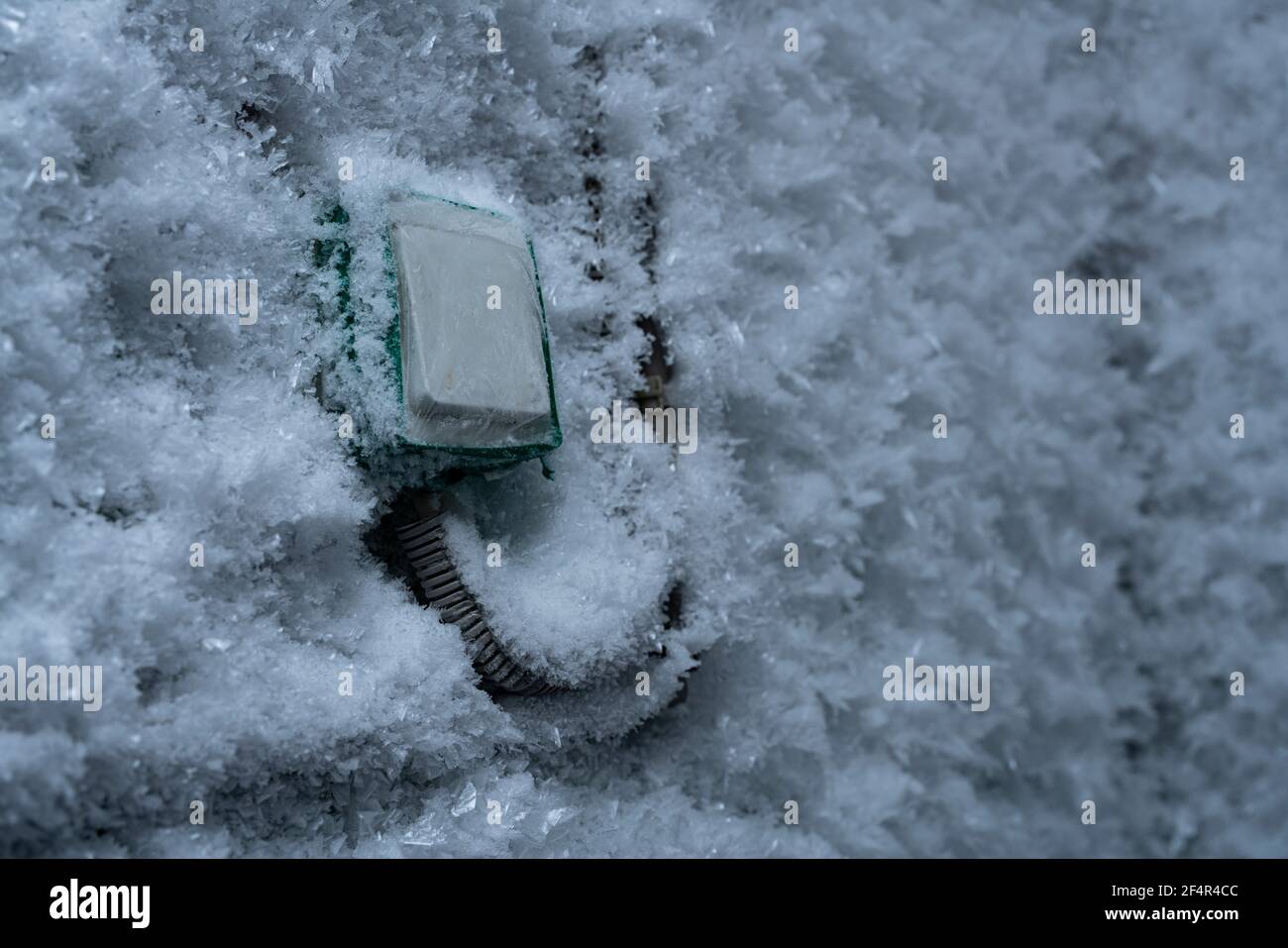 Snow covered device with switch on frozen wall in winter Stock Photo