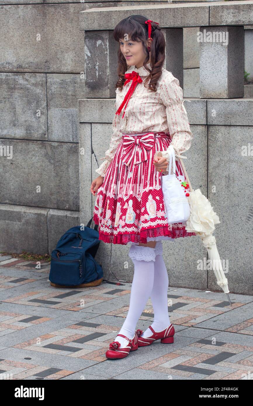 Full length photo of Japanese lolita wearing red and white skirt, long frilly white socks and red shoes posing for photograph, Harajuku, Tokyo, Japan Stock Photo