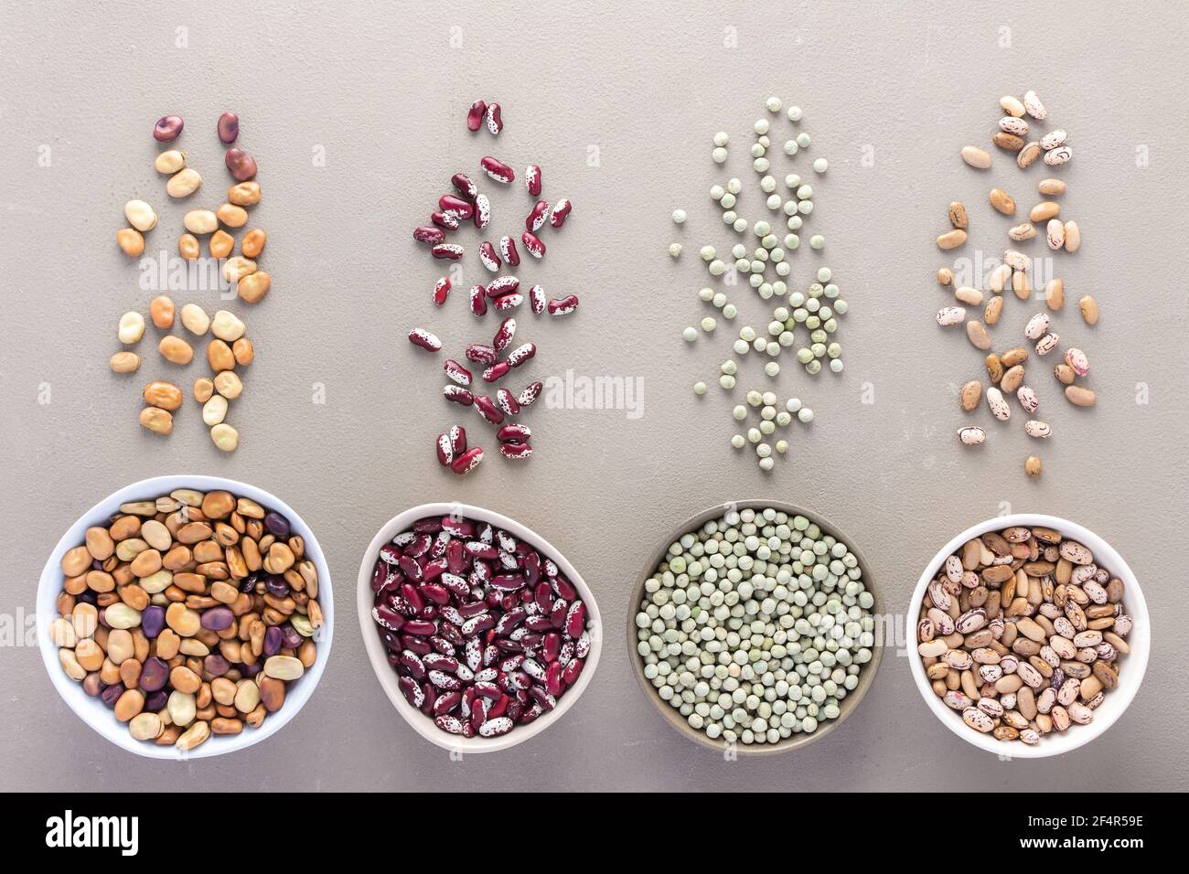 Different types of legumes in bowls and scattered in the background
