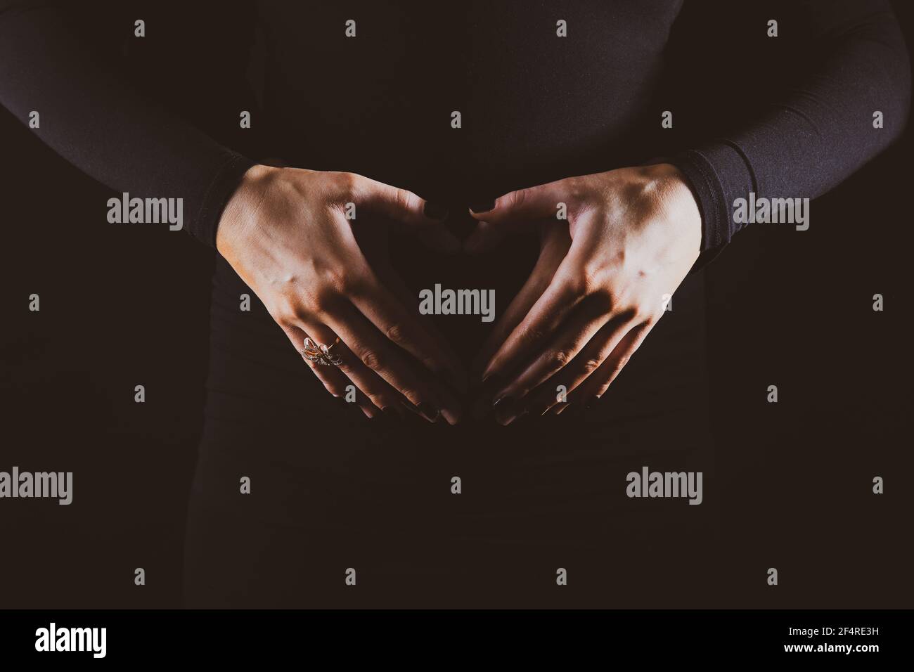 A pregnant mother holding her tummy in the shape of a heart Stock Photo