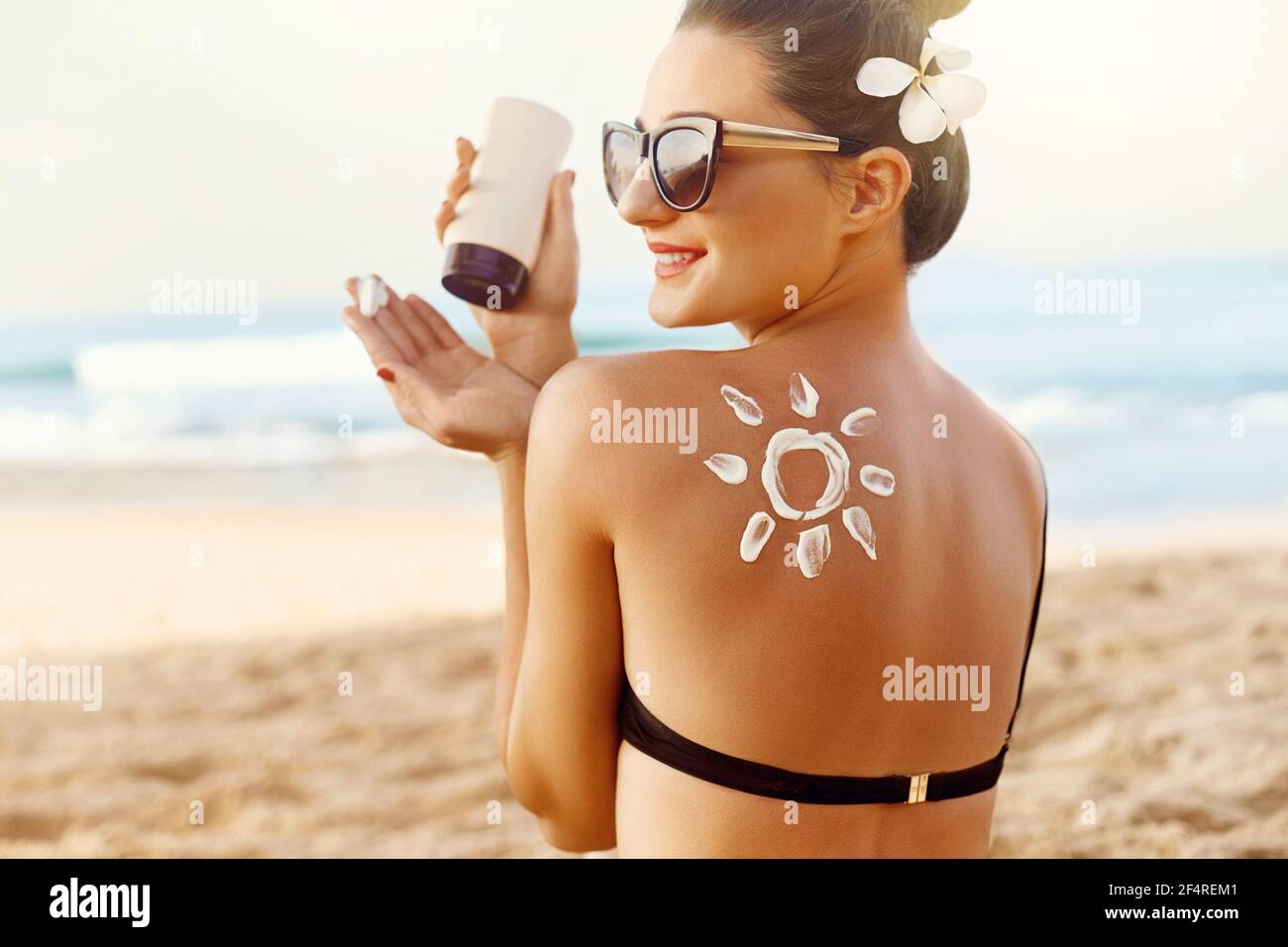 Woman Applying Sun Cream  on Tanned  Shoulder In Form Of The Sun. Sun Protection.Sun Cream. Skin and Body Care. Girl Using Sunscreen to Skin. Female H Stock Photo