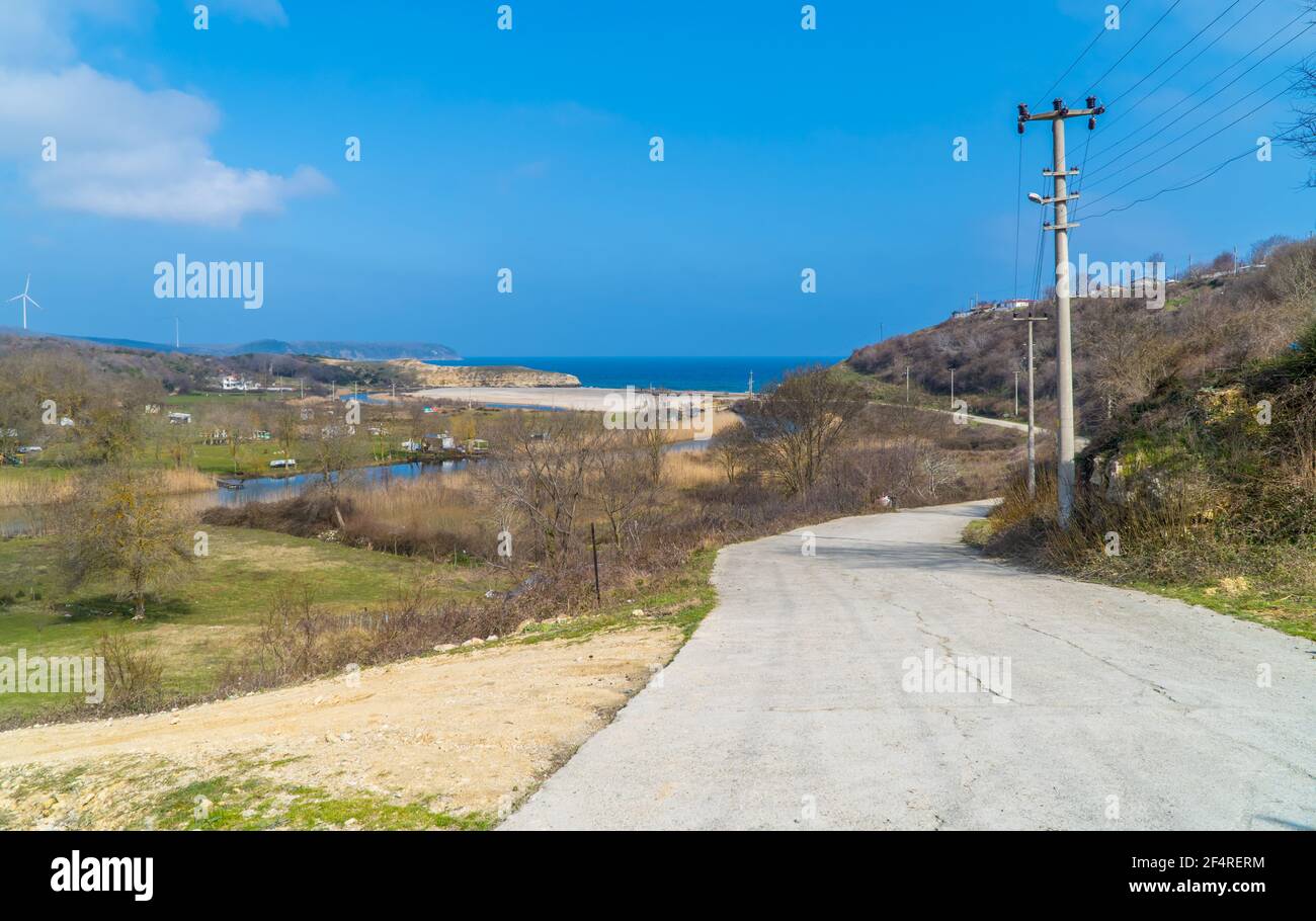 Road leading to the beach in the Black Sea town of Kiyikoy in northwestern Turkey with windfarms in the background Stock Photo