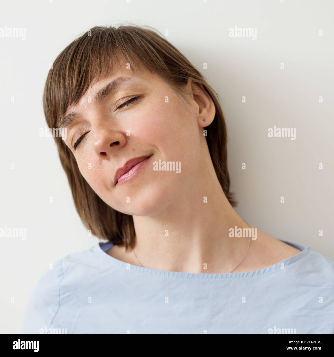Portrait of a Woman with closed eyes with a short haircut on a light ...