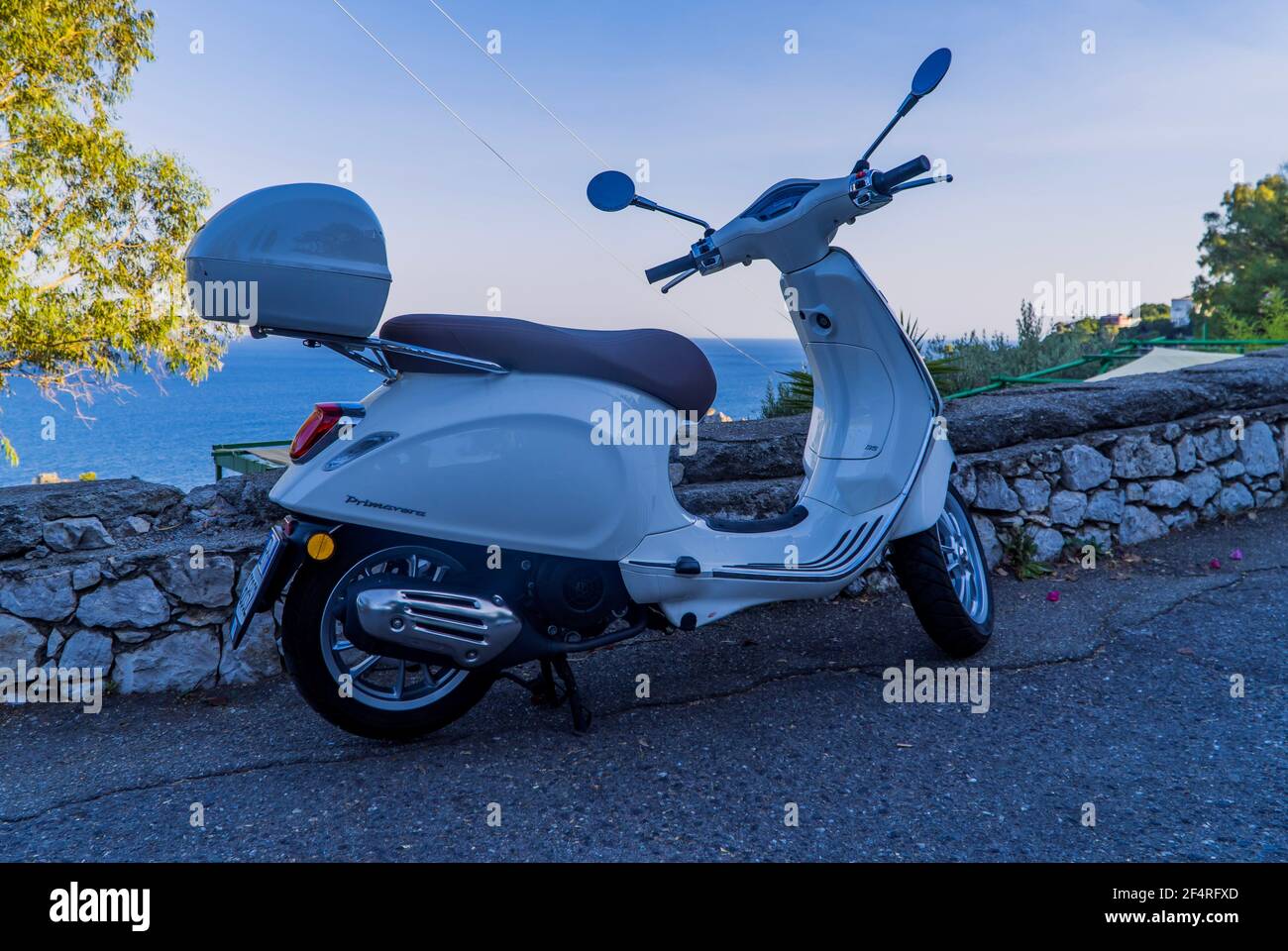 Taormina, Italy - July 25, 2020 - white Italian Vespa motorbike on a hill with the sea in the background in Sicily Stock Photo