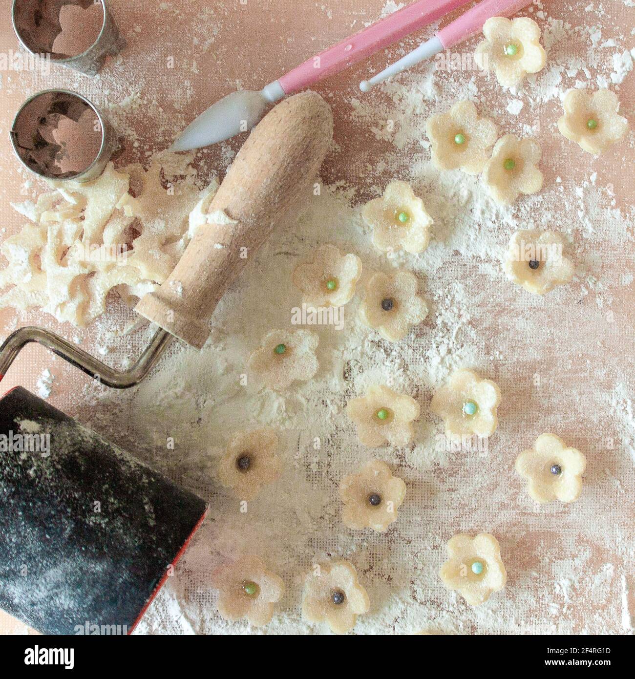 White marzipan flowers being prepared for cake decorating with fondant tools and cookie cutters. Stock Photo