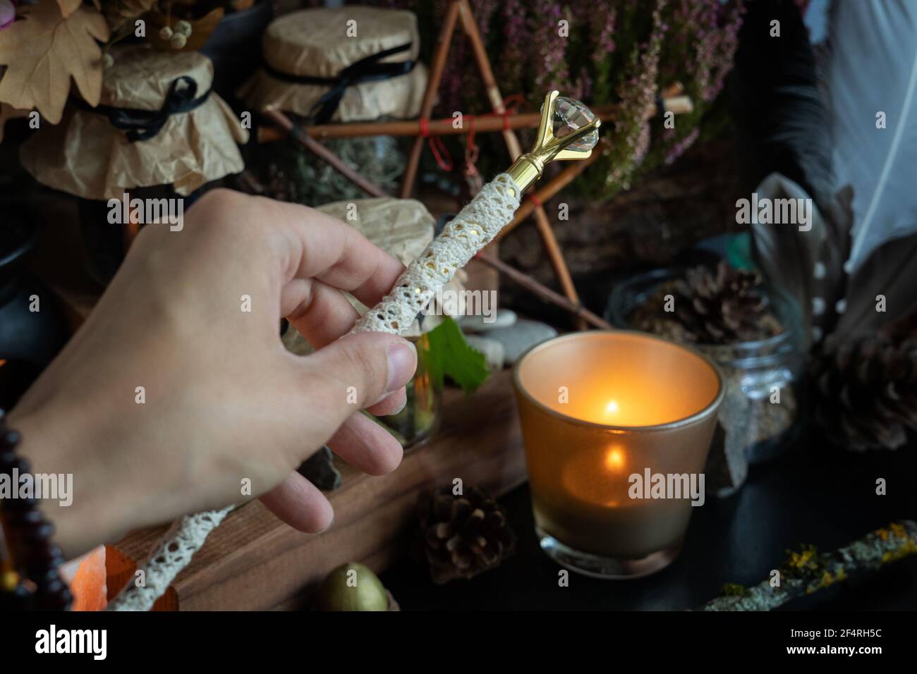 Woman hand is holding magic wand performing a pagan ritual. Stock Photo