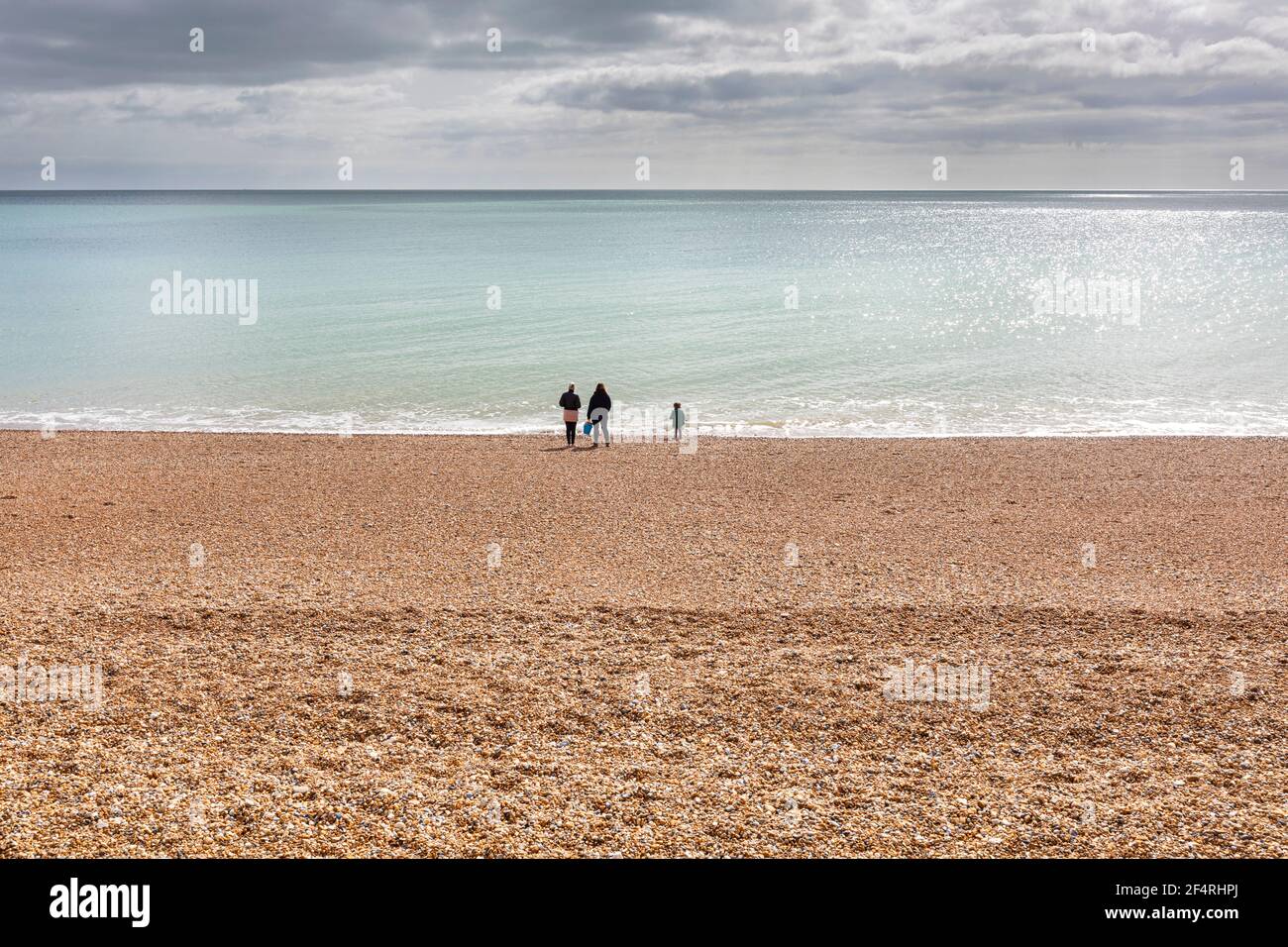 A family of three on an empty beach during covid 19 lockdown Stock Photo
