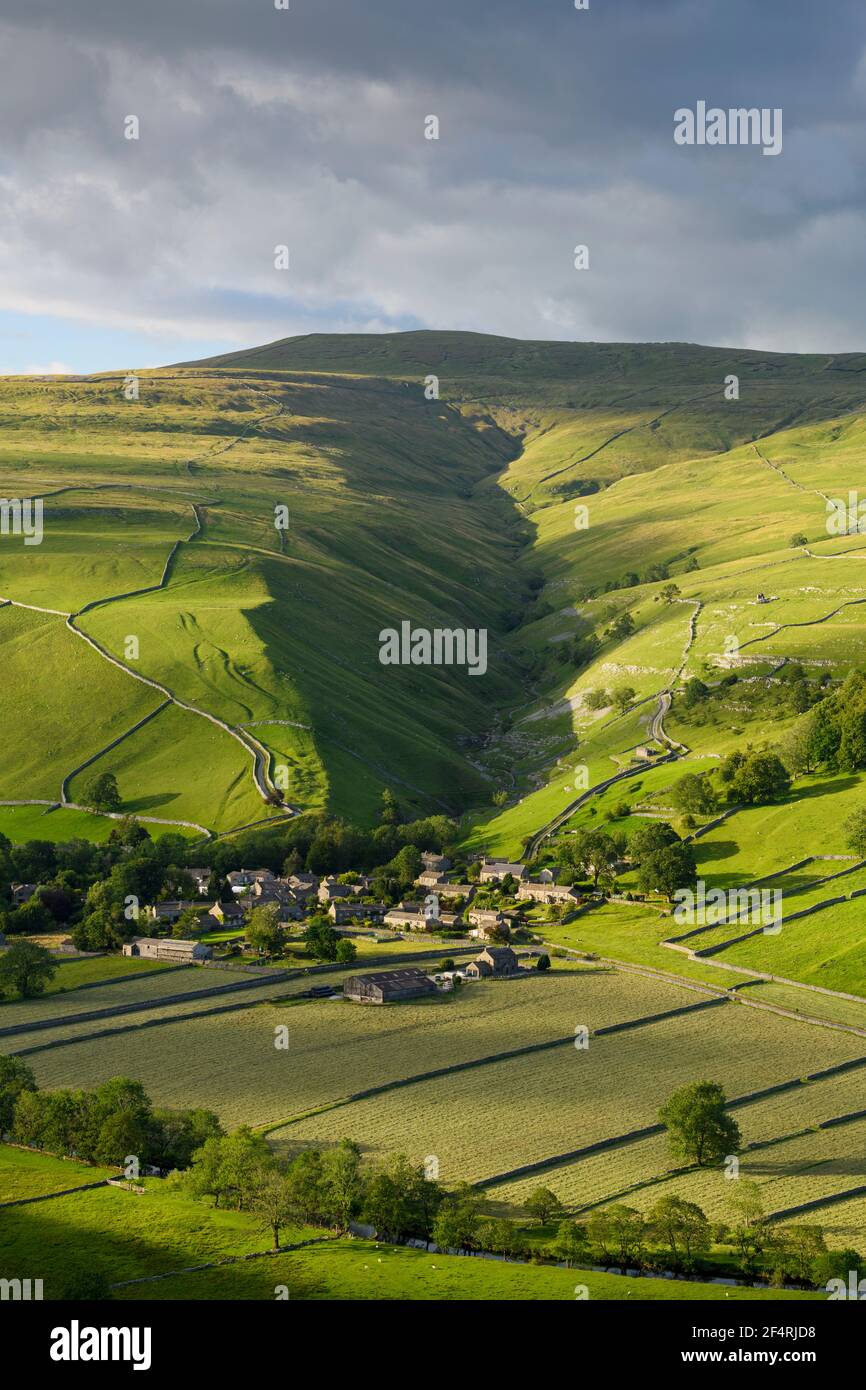 Scenic Dales village (houses) nestling in valley by dry-stone walls, hillside slopes & steep-sided Cam Gill gorge - Starbotton, Yorkshire England, UK. Stock Photo