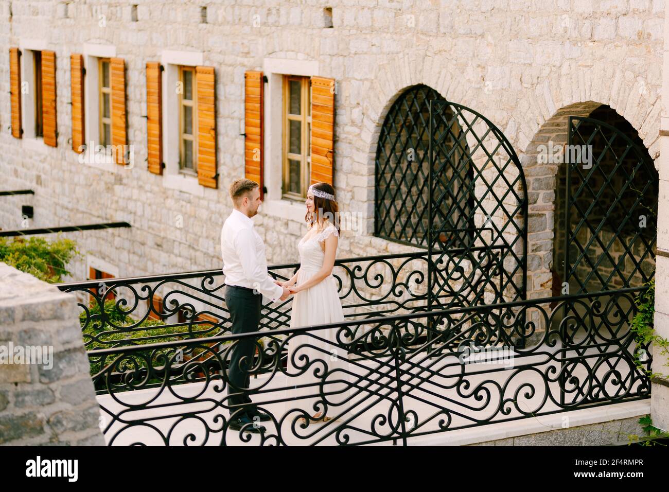 The bride and groom stand on a beautiful forged bridge in the old town ...