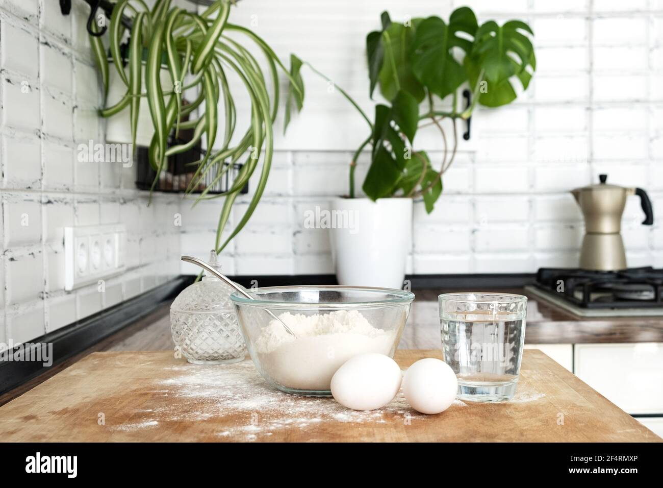 Pouring Water into Flour. Making dough by female hands in white moden