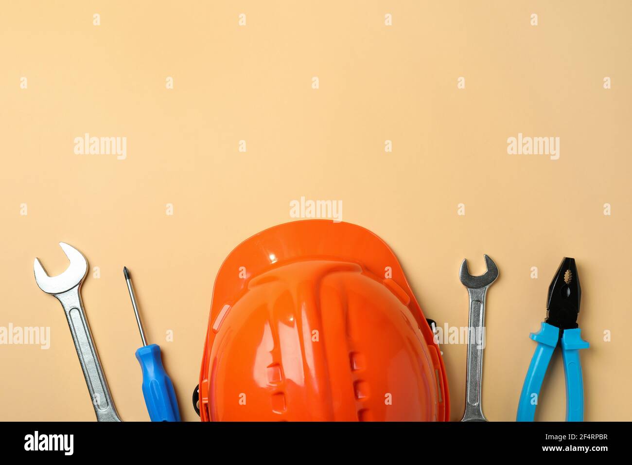 Hard hat and tools on beige background Stock Photo