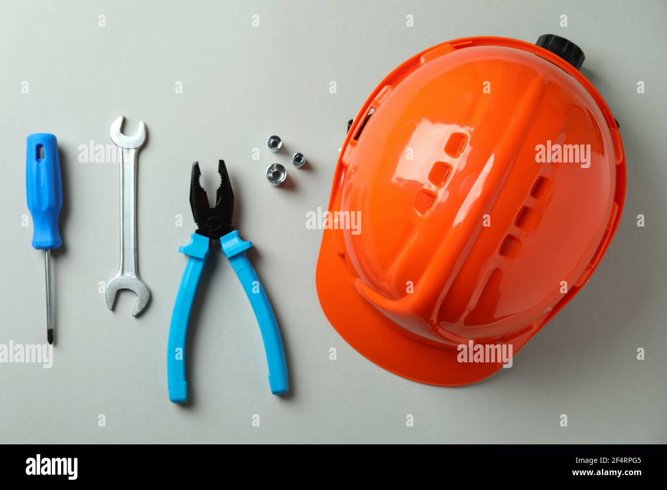 Hard hat and working tools on light gray background Stock Photo