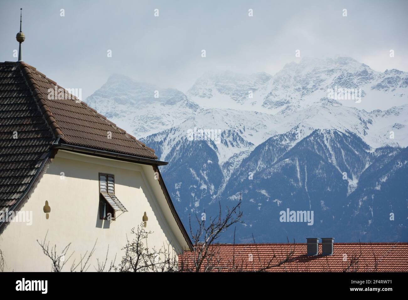 Snow-capped mountains and rooftop in Mals / Malles, Val Venosta / Vinschgau, South Tirol, Italy, near the Swiss and Austrian border. Stock Photo